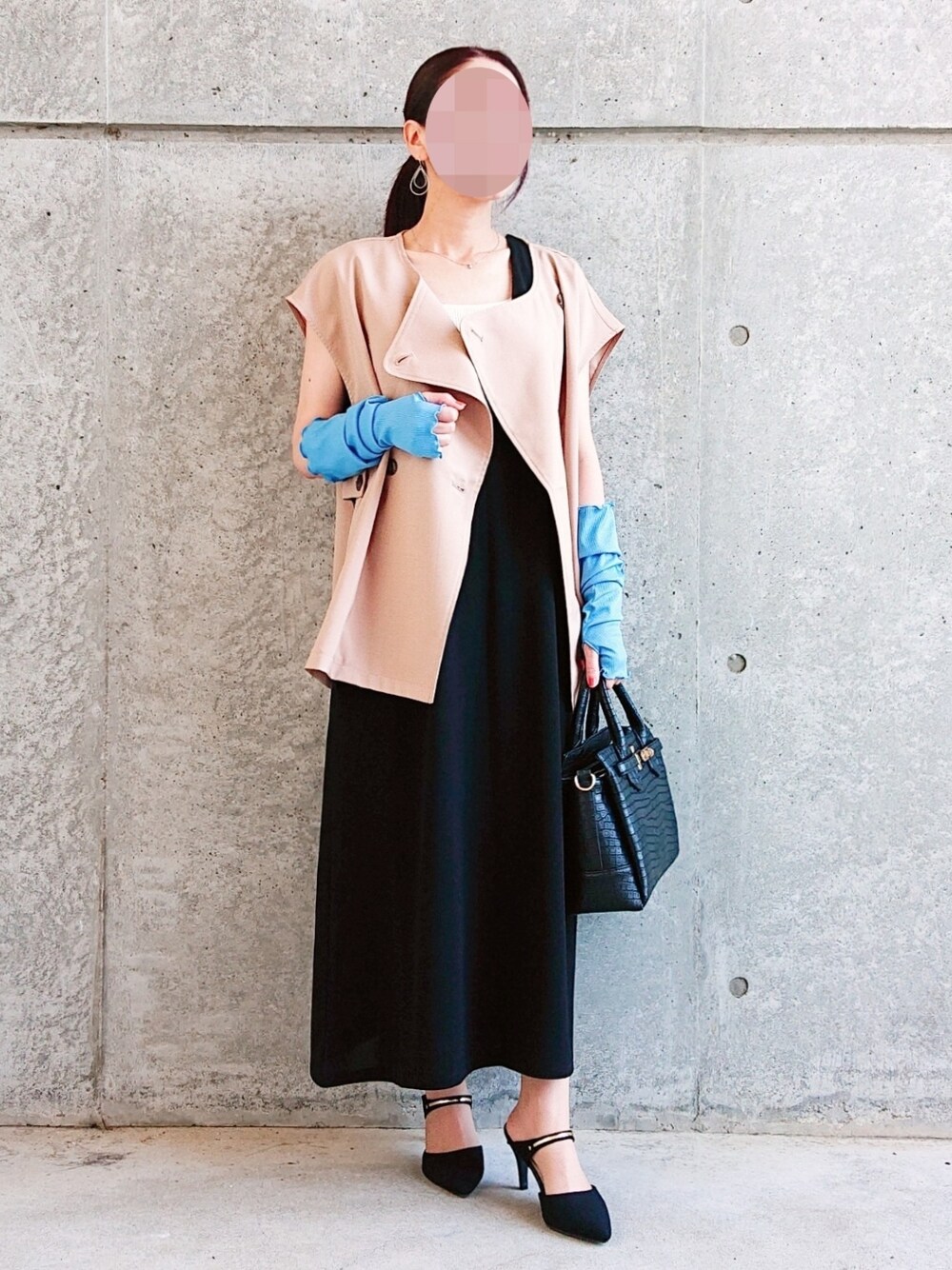 ベージュ系のベスト、ホワイト系のタンクトップ、ブラック系のジャンパースカートを着用したレディースの秋コーディネートの1枚目の写真