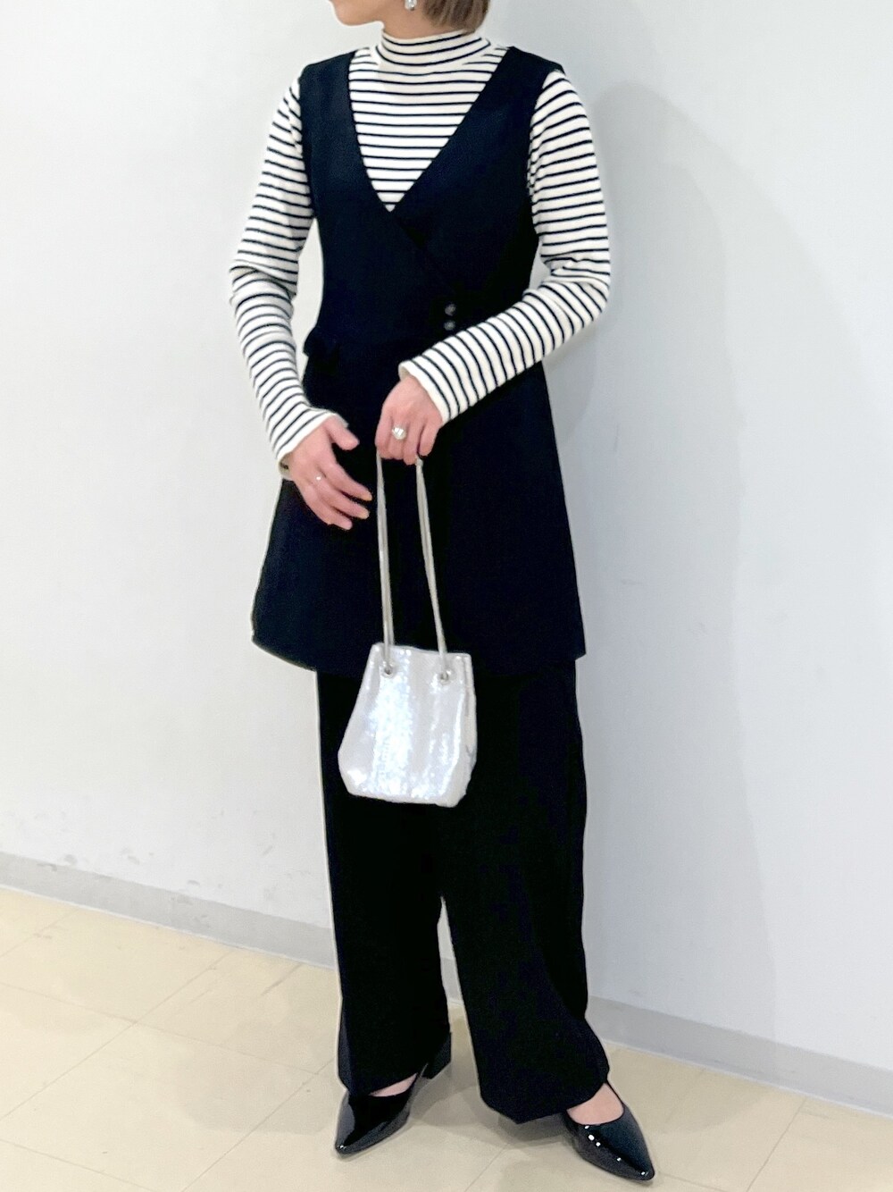 ホワイト系のニット/セーター、ブラック系のワンピース、ブラック系のスラックスを着用したレディースの冬コーディネートの1枚目の写真