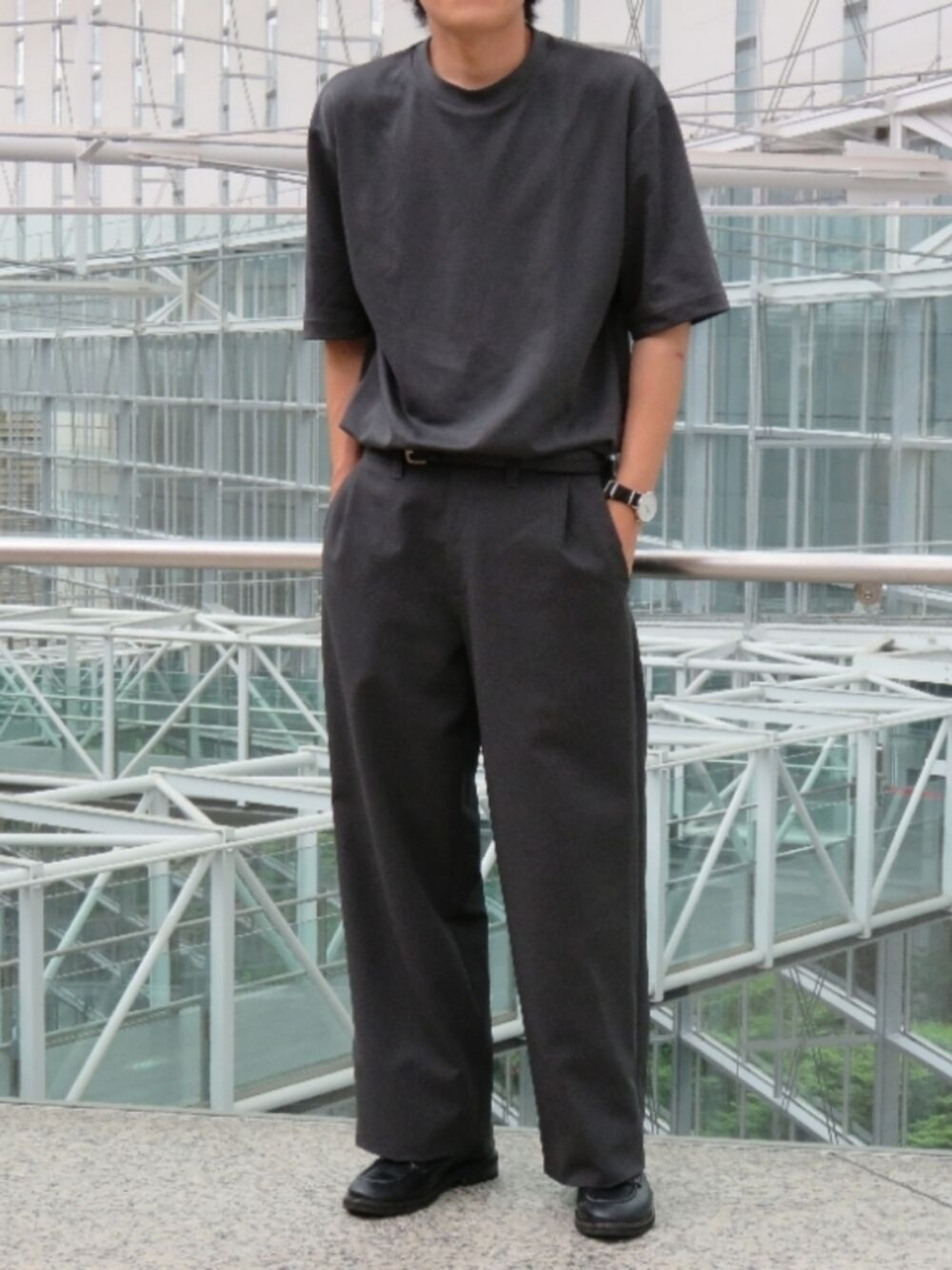 グレー系のスラックス、ブラック系のドレスシューズ、その他のTシャツ/カットソーを着用したメンズの夏コーディネートの1枚目の写真