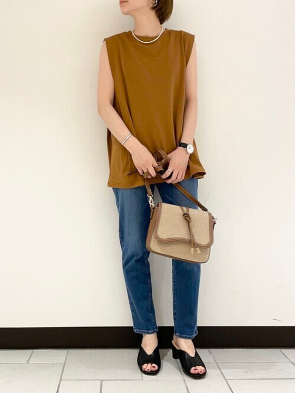 ブルー系のデニムパンツ、ブラウン系のTシャツ/カットソー、ブラック系のサンダルを着用したレディースの夏コーディネートの1枚目の写真