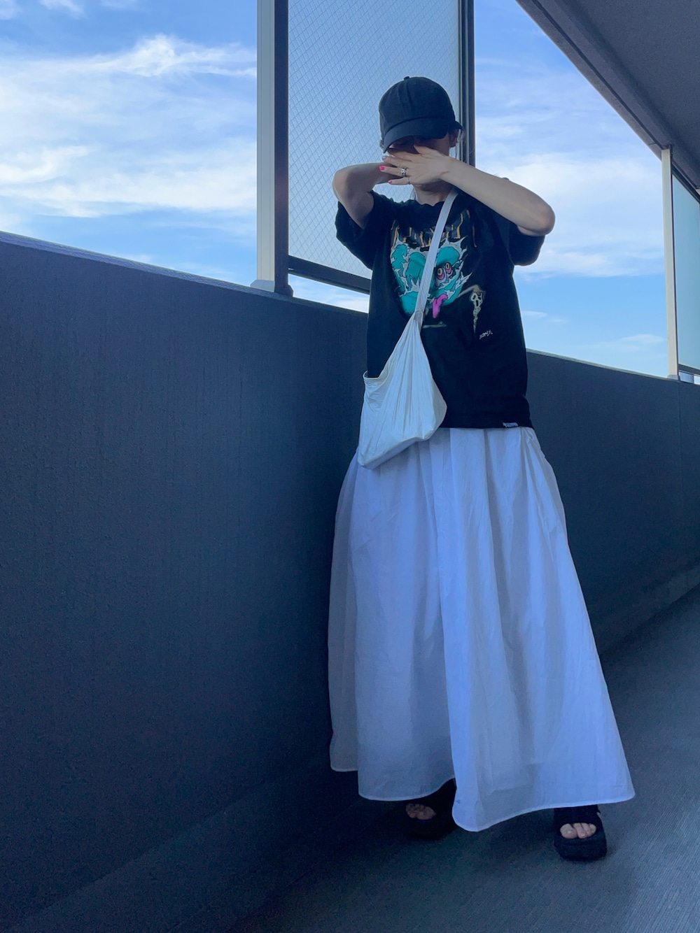 ブラック系のTシャツ/カットソー、ホワイト系のショルダーバッグ、ホワイト系のスカートを着用したレディースの夏コーディネートの1枚目の写真