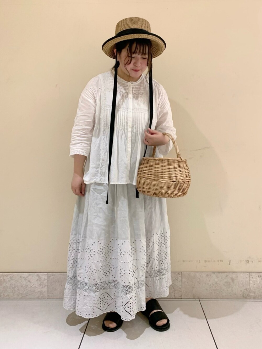 ホワイト系のシャツ/ブラウス、ホワイト系のかごバッグ、ブラック系のサンダルを着用したレディースの夏コーディネートの1枚目の写真