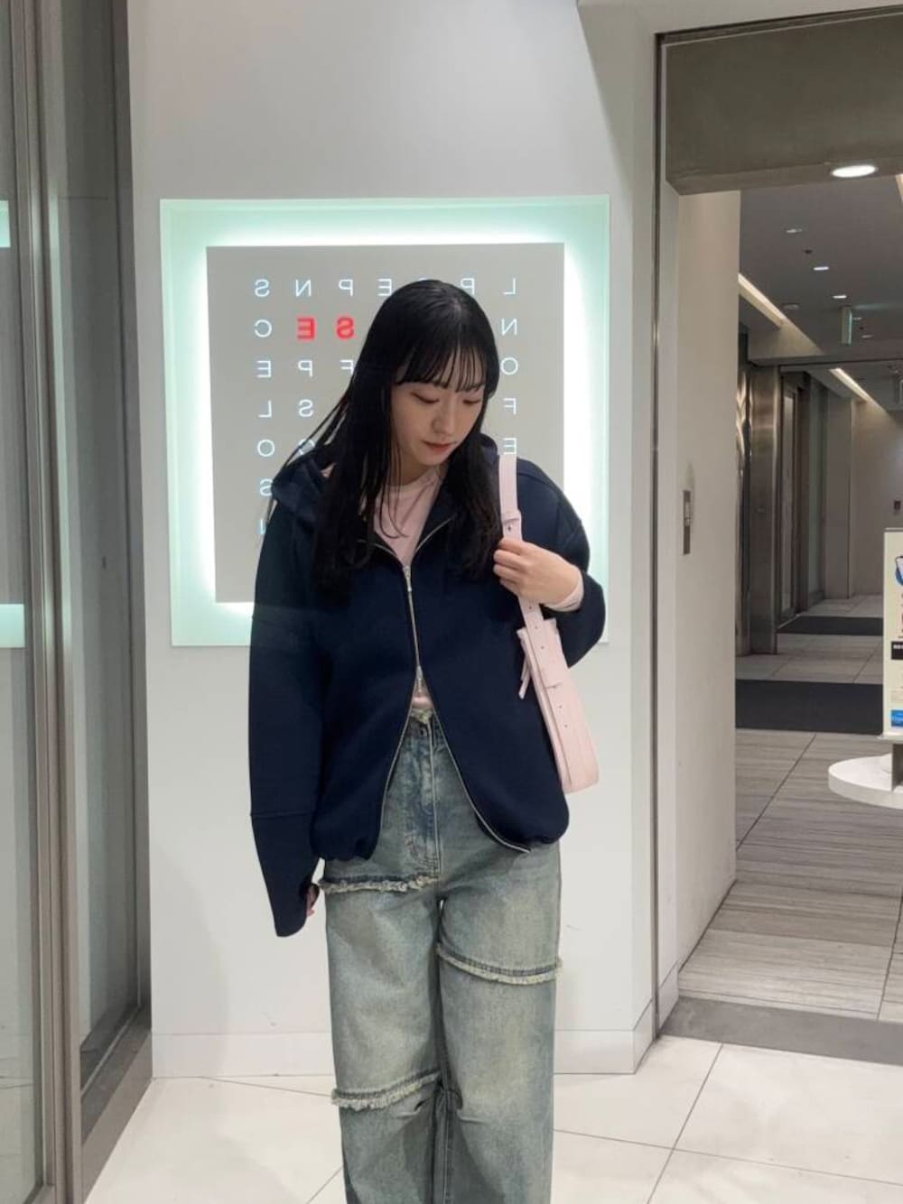 ピンク系のTシャツ/カットソー、ブルー系のデニムパンツ、ピンク系のショルダーバッグを着用したレディースの冬コーディネートの1枚目の写真