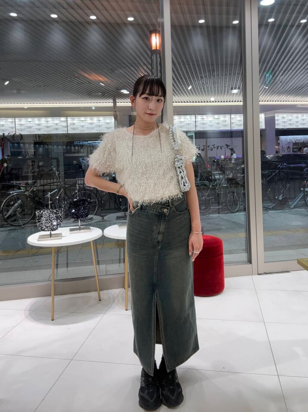 シルバー系のハンドバッグ、ホワイト系のTシャツ/カットソー、ブラウン系のスカートを着用したレディースの夏コーディネートの1枚目の写真