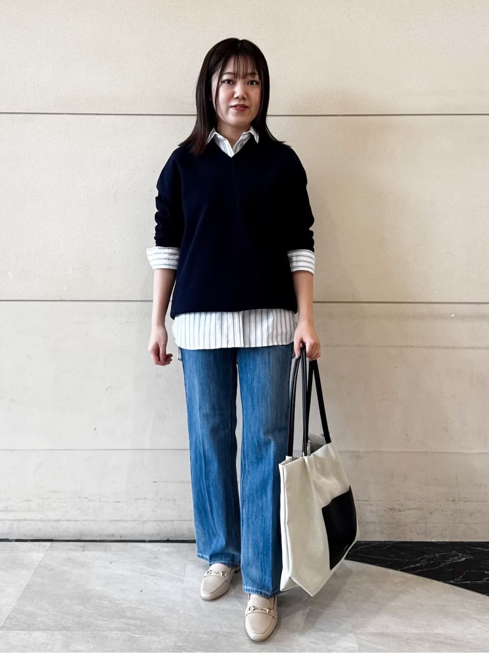 ブルー系のニット/セーター、グレー系のシャツ/ブラウス、ブルー系のデニムパンツを着用したレディースの冬コーディネートの1枚目の写真