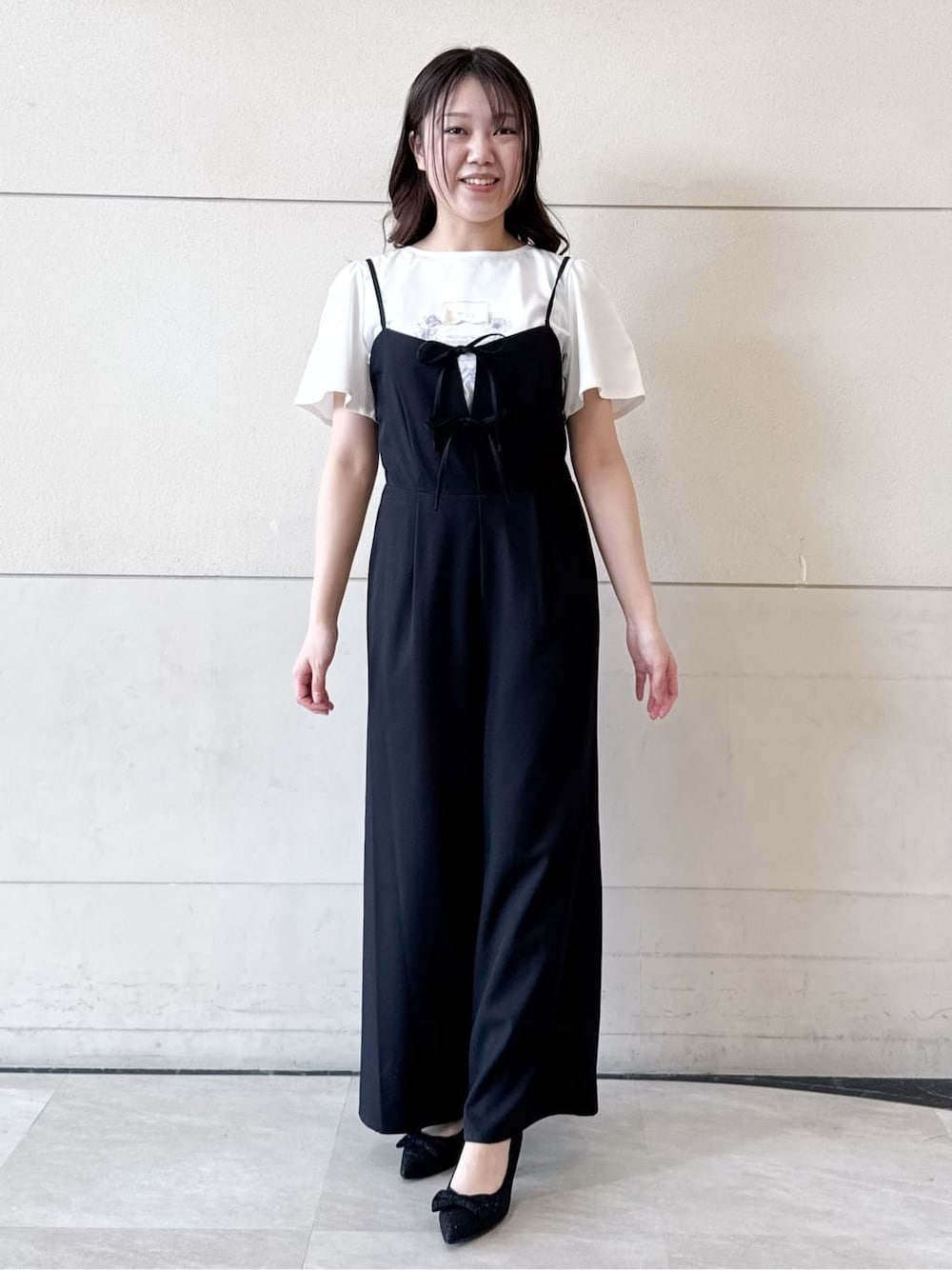 ベージュ系のパーカー、ホワイト系のTシャツ/カットソー、ブラック系のサロペット/オーバーオールを着用したレディースの春コーディネートの1枚目の写真