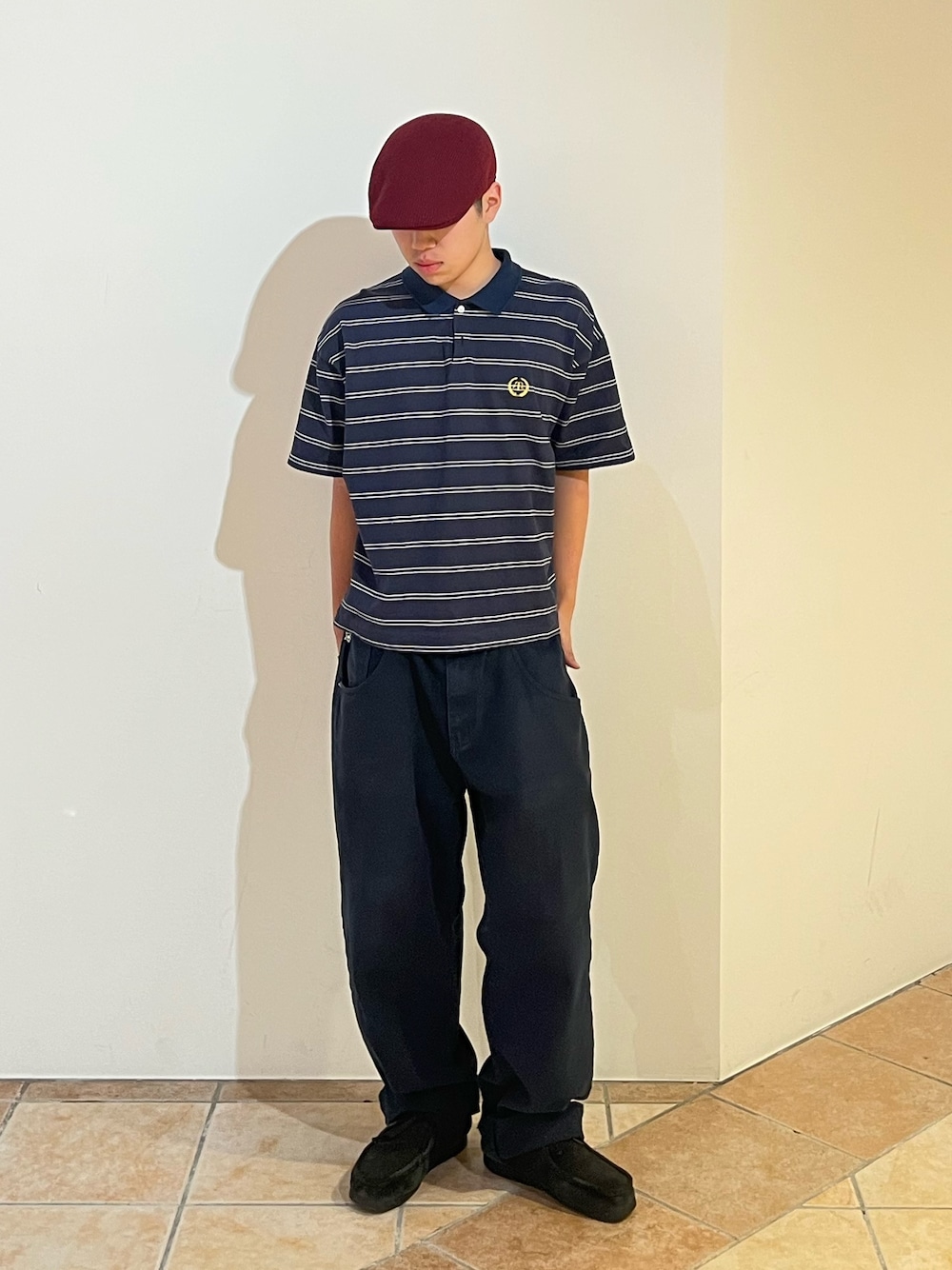 ブルー系のポロシャツ、ブラック系のデニムパンツ、レッド系のハンチング/ベレー帽を着用したメンズの夏コーディネートの1枚目の写真