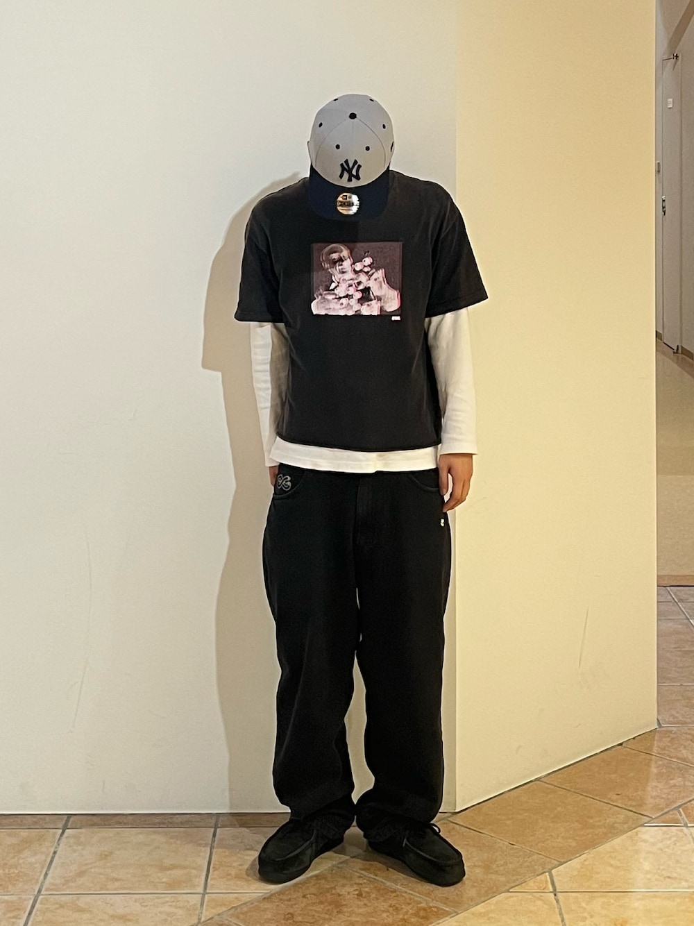 ブラック系のデニムパンツ、ブラック系のTシャツ/カットソー、ブラック系のブーツを着用したメンズの秋コーディネートの1枚目の写真