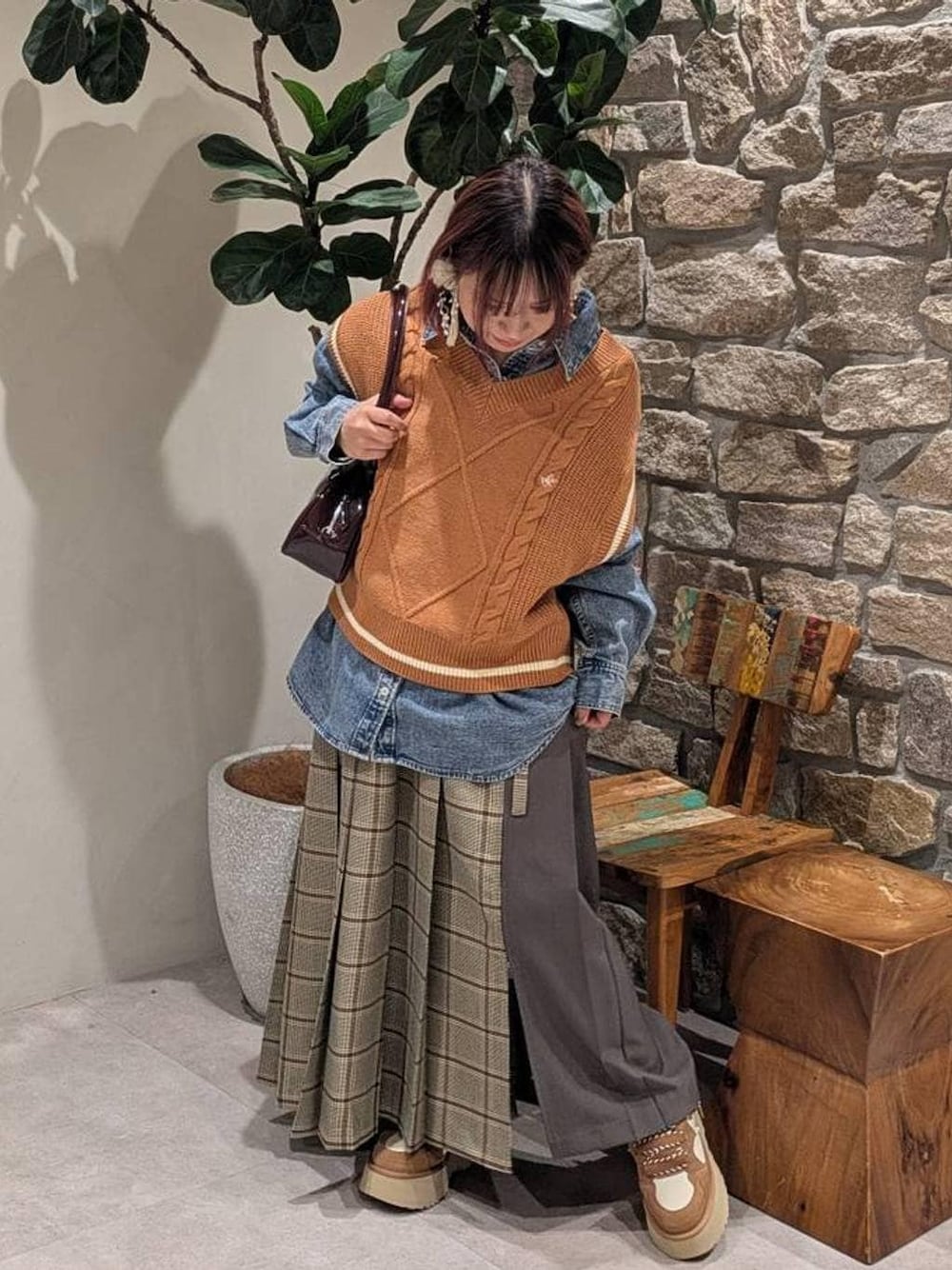 イエロー系のベスト、ブルー系のシャツ/ブラウス、ベージュ系のスカートを着用したレディースの冬コーディネートの1枚目の写真