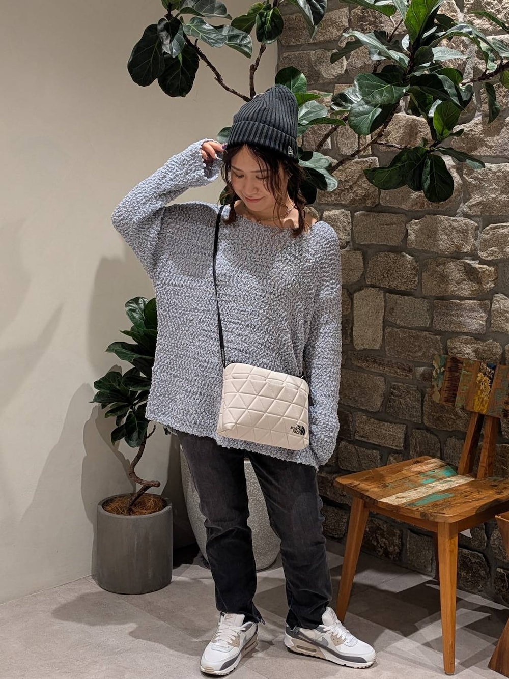ブルー系のニット/セーター、ベージュ系のショルダーバッグ、グレー系のデニムパンツを着用したレディースの夏コーディネートの1枚目の写真