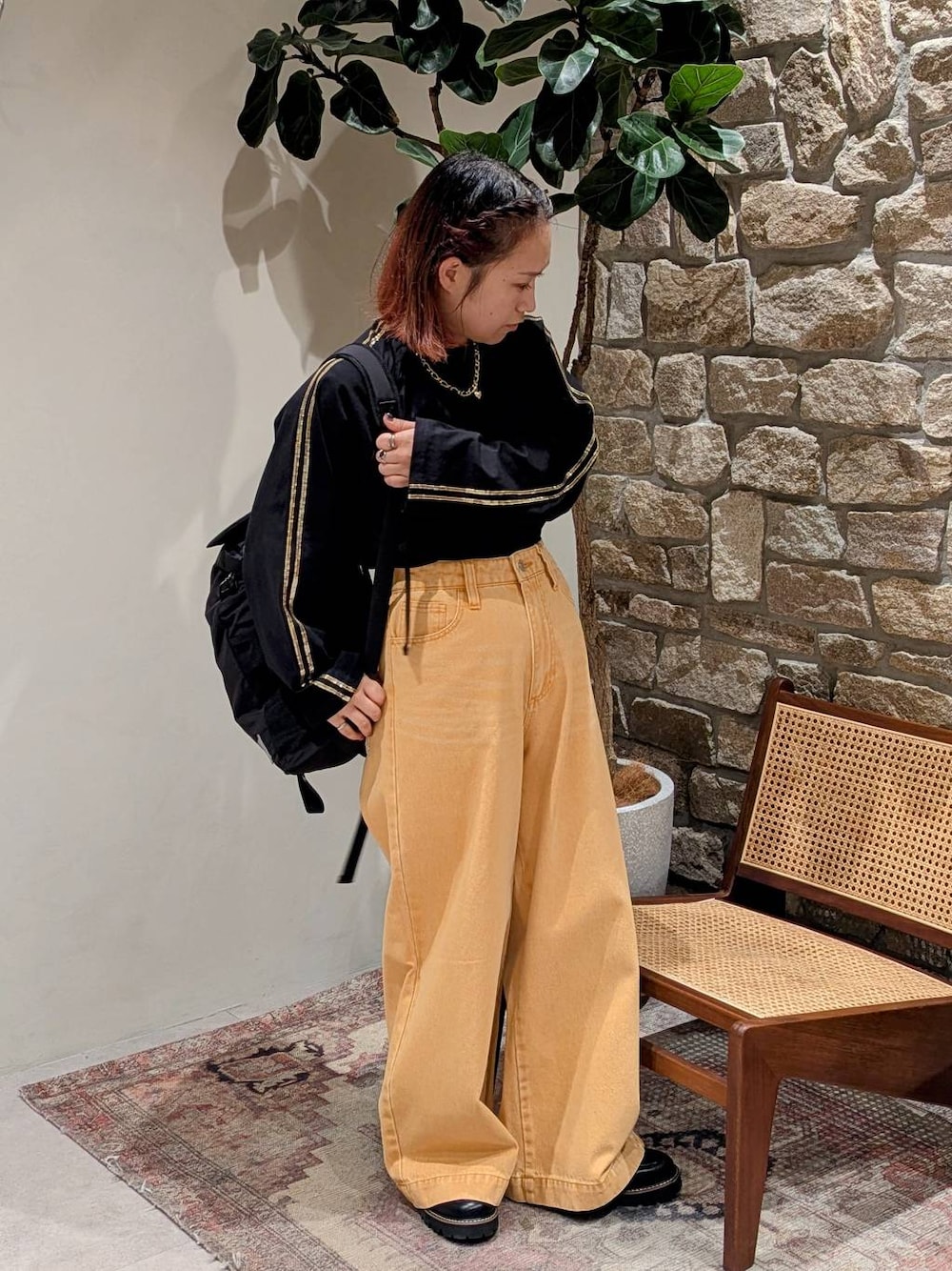 ブラック系のバックパック/リュック、ブラック系のローファー、オレンジ系のデニムパンツを着用したレディースの冬コーディネートの1枚目の写真