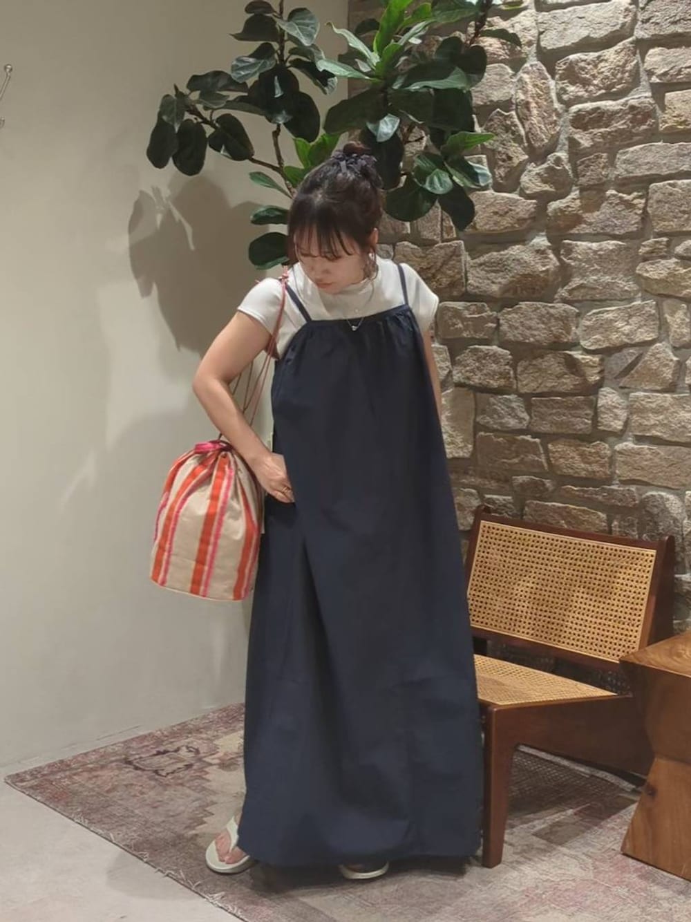 ピンク系のハンドバッグ、グレー系のサンダル、ブルー系のジャンパースカートを着用したレディースの春コーディネートの1枚目の写真