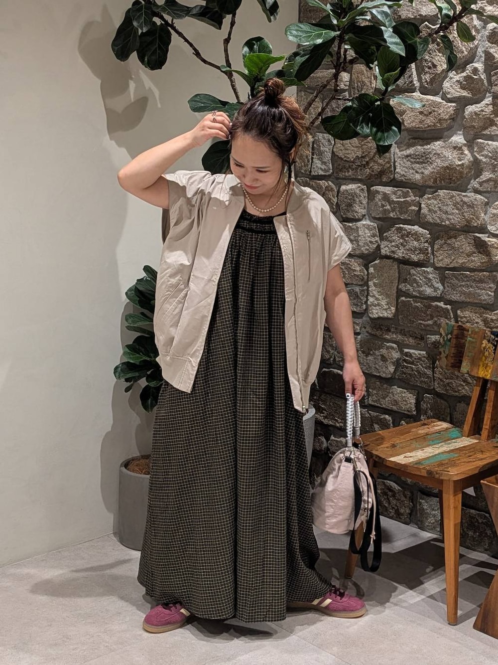イエロー系のワンピース、ブラウン系のタンクトップ、ベージュ系のブルゾンを着用したレディースの夏コーディネートの1枚目の写真