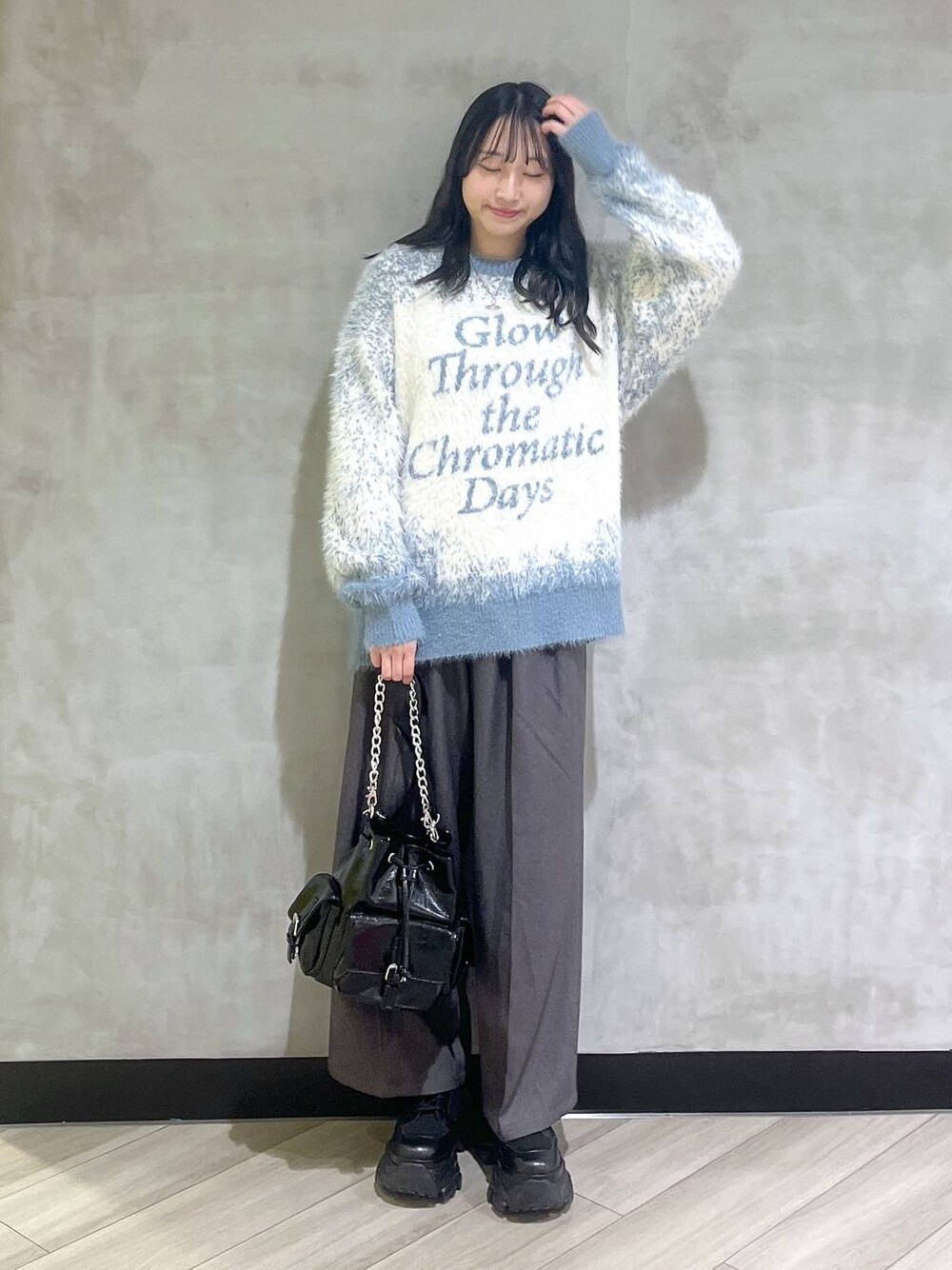 ブラック系のスニーカー、ブルー系のニット/セーター、グレー系のスラックスを着用したレディースの秋コーディネートの1枚目の写真