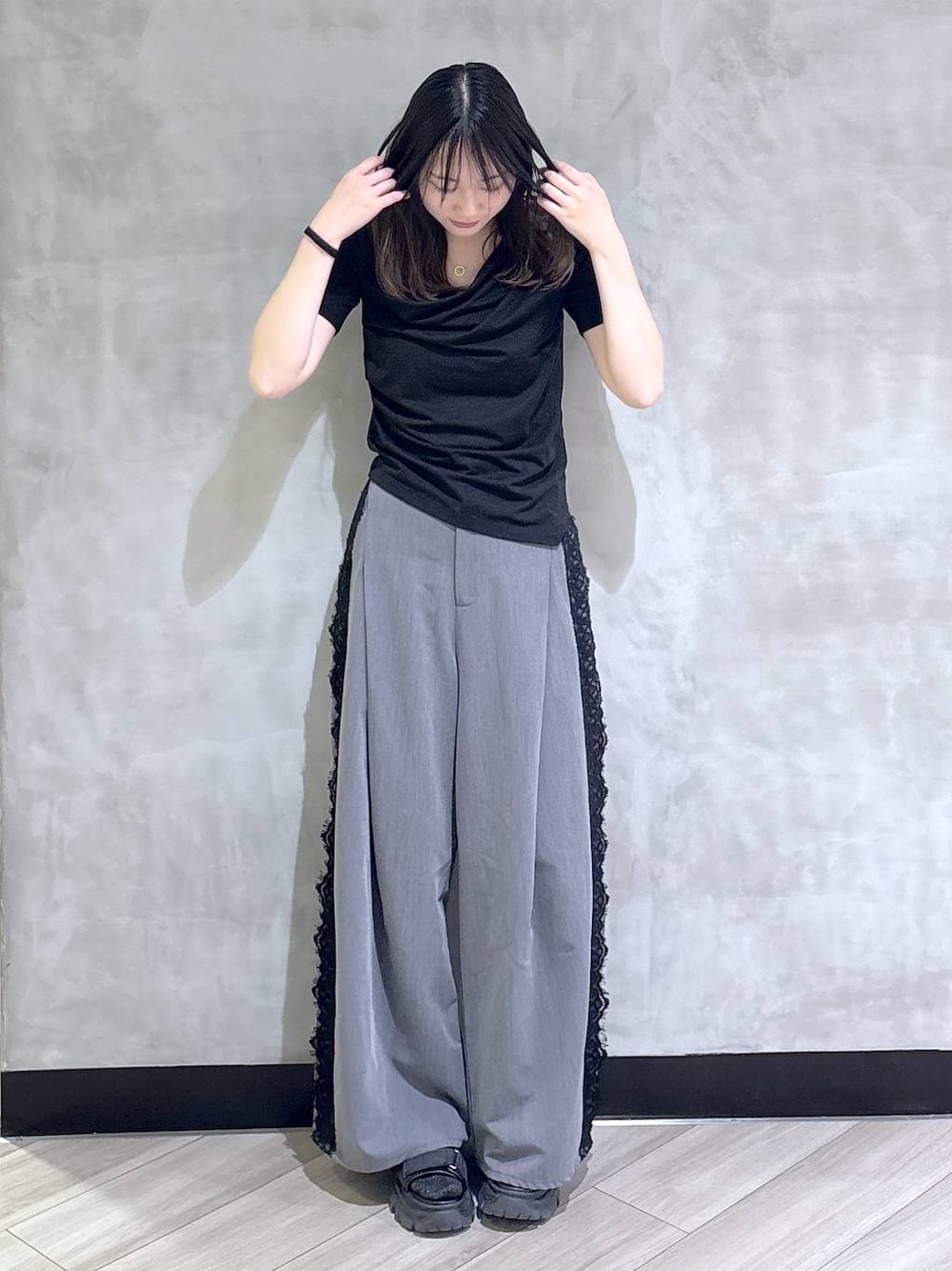 ブラック系のサンダル、グレー系のスラックス、ブラック系のTシャツ/カットソーを着用したレディースの夏コーディネートの1枚目の写真