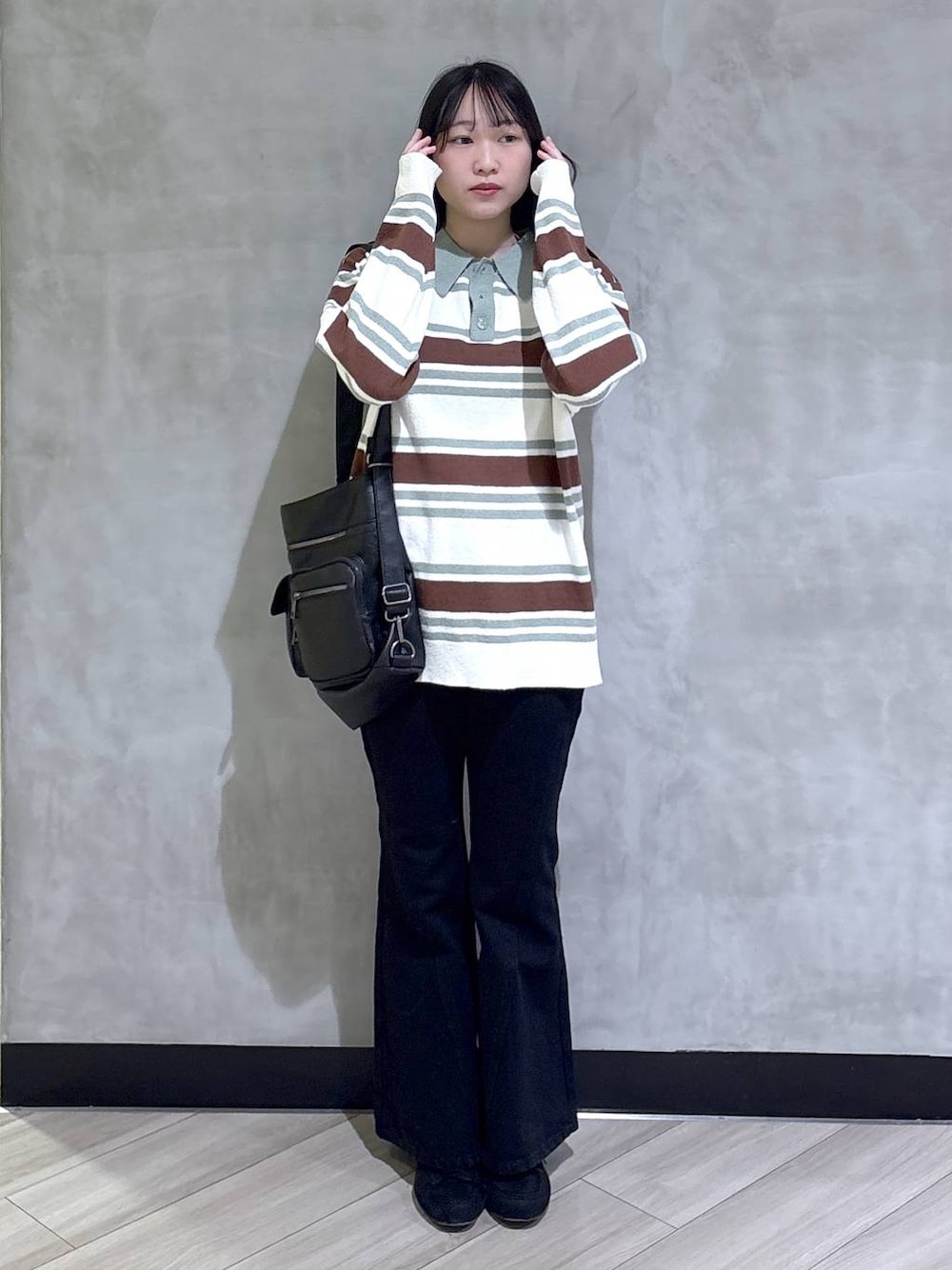 ブラック系のデニムパンツ、ブラック系のモカシン/デッキシューズ、グリーン系のニット/セーターを着用したレディースの春コーディネートの1枚目の写真