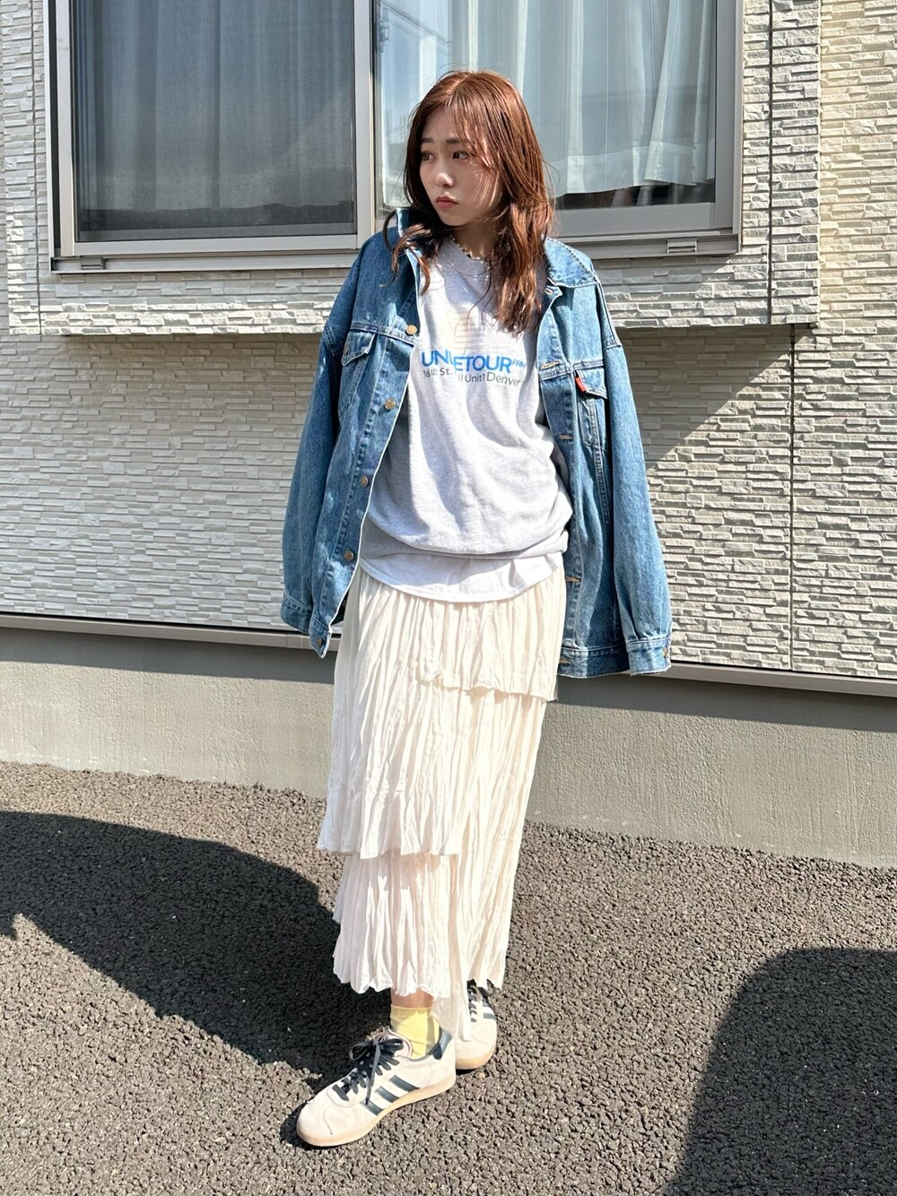 ブルー系のデニムジャケット、グレー系のスウェット、ホワイト系のスカートを着用したレディースの春コーディネートの1枚目の写真