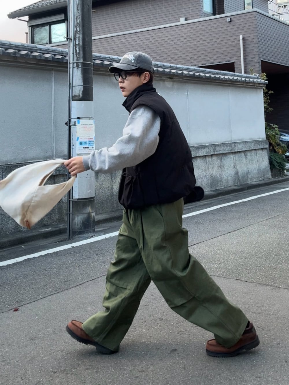 グレー系のスウェット、ブラック系のダウンベスト、グリーン系のチノパンツを着用したメンズの冬コーディネートの1枚目の写真