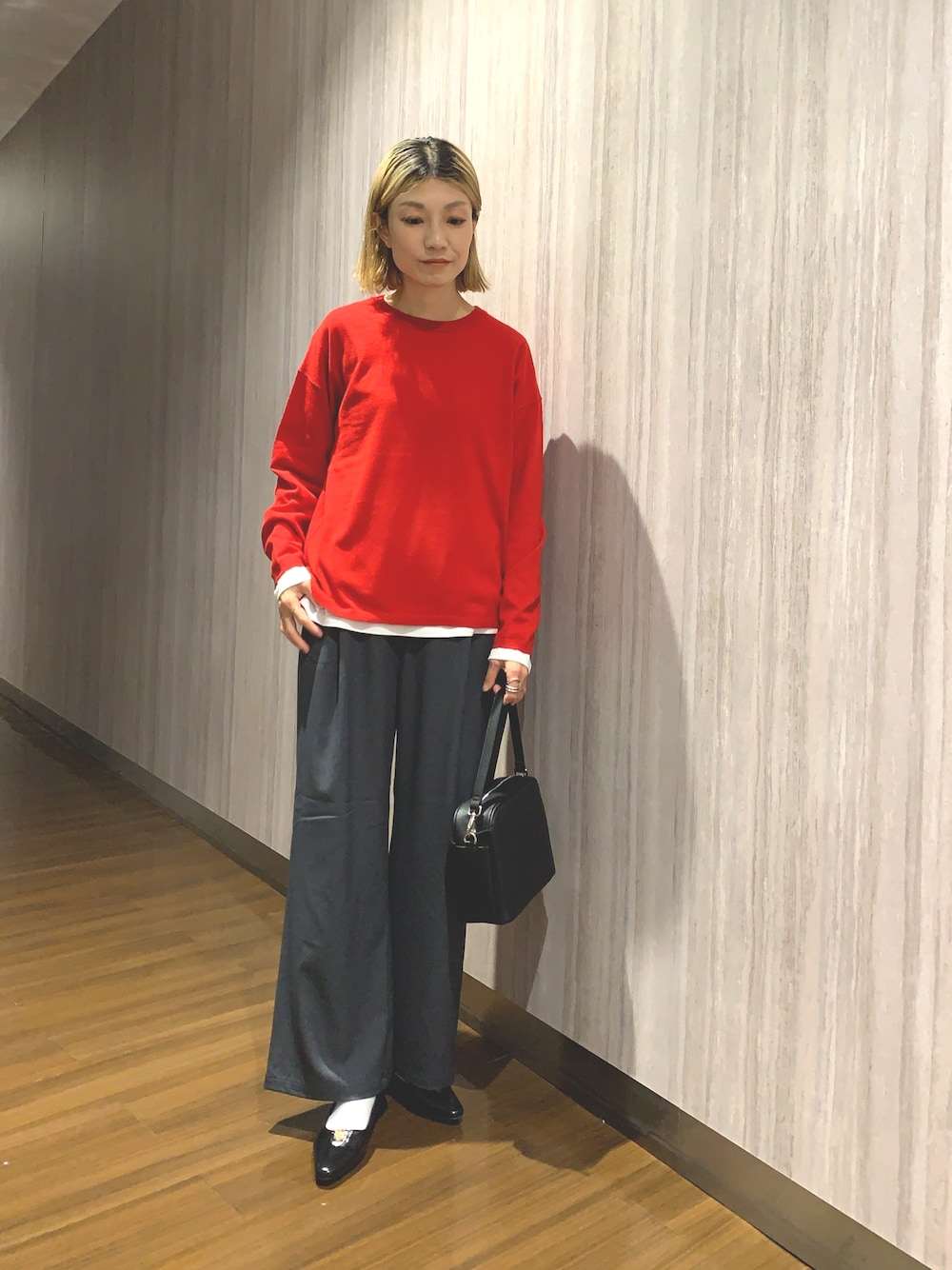レッド系のニット/セーター、グレー系のその他パンツ、ブラック系のショルダーバッグを着用したレディースの秋コーディネートの1枚目の写真