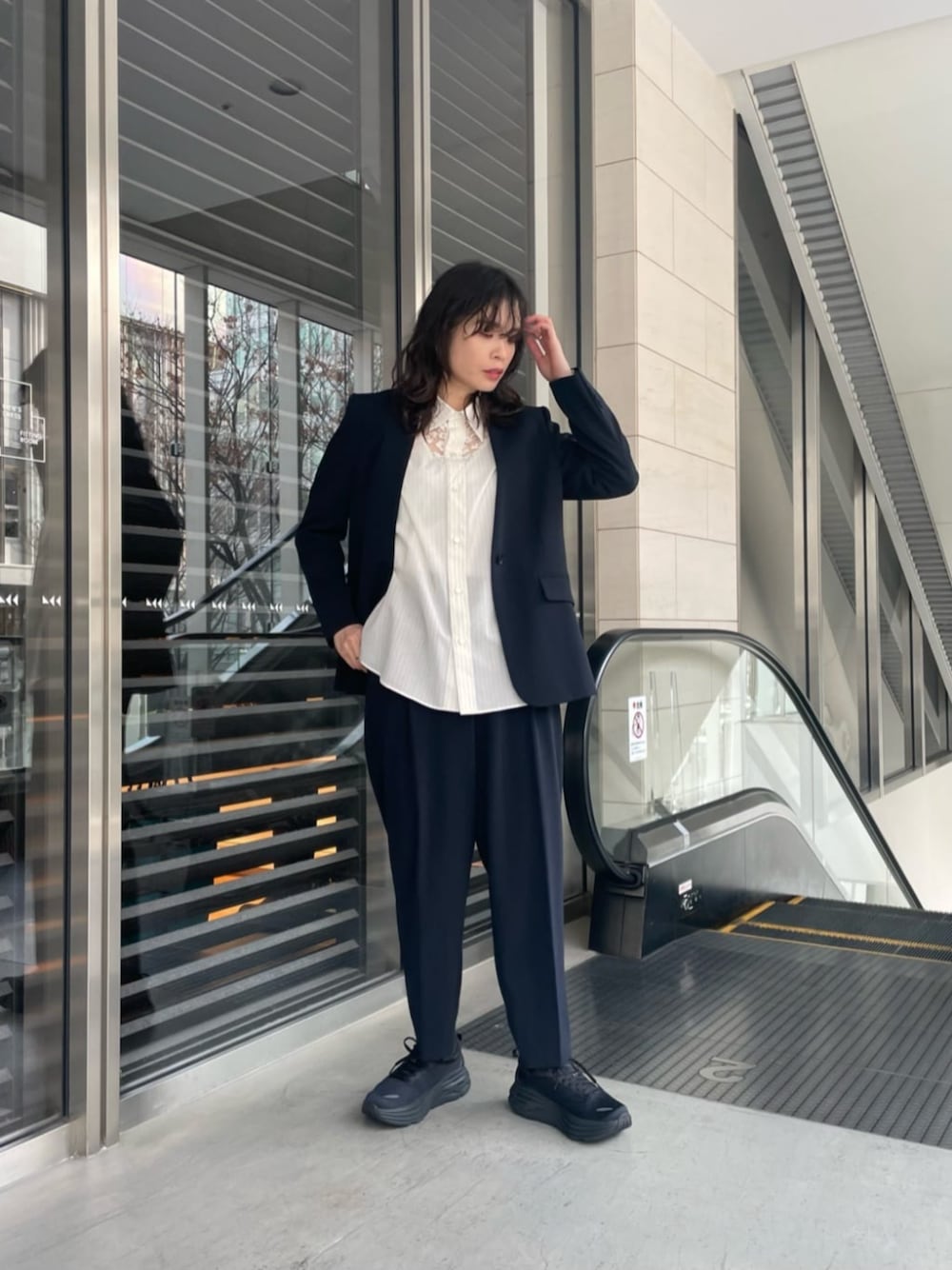 ブラック系のスニーカー、ブルー系のノーカラージャケット、ホワイト系のシャツ/ブラウスを着用したレディースの冬コーディネートの1枚目の写真