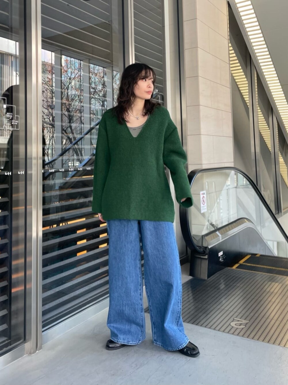 グリーン系のニット/セーター、ブルー系のデニムパンツ、グリーン系のTシャツ/カットソーを着用したレディースの冬コーディネートの1枚目の写真