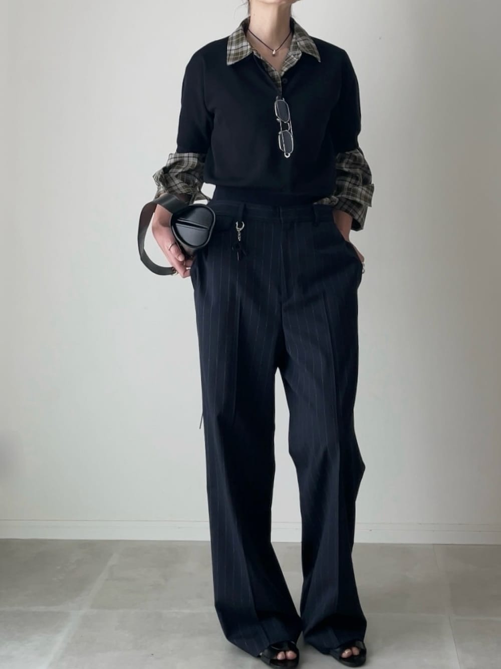 ブラック系のニット/セーター、グリーン系のシャツ/ブラウス、ブルー系のスラックスを着用したレディースの春コーディネートの1枚目の写真