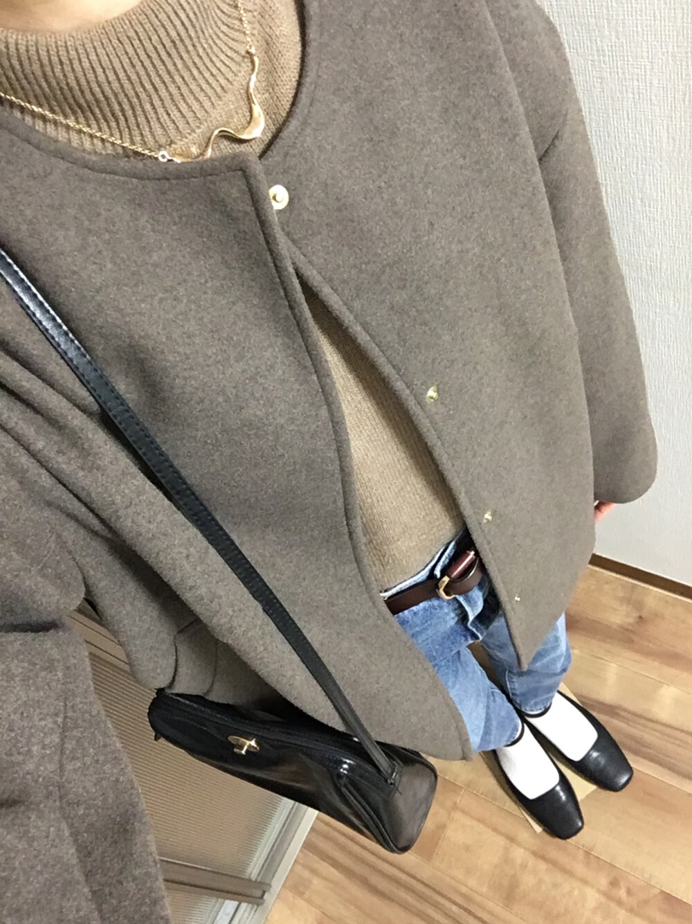 ブラック系のパンプス、ブラウン系のノーカラーコート、ブラウン系のニット/セーターを着用したレディースの冬コーディネートの1枚目の写真