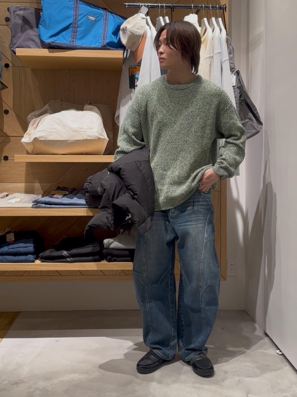 グリーン系のニット/セーター、ブラック系のブルゾン、ブルー系のデニムパンツを着用したメンズの冬コーディネートの1枚目の写真