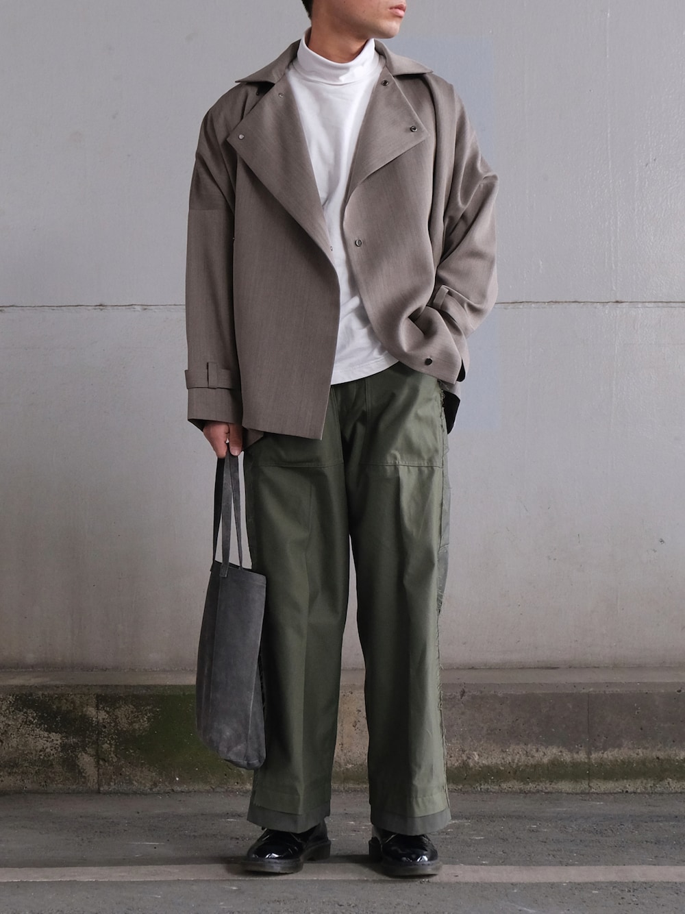 グレー系のトレンチコート、ホワイト系のTシャツ/カットソー、グリーン系のカーゴパンツを着用したメンズの冬コーディネートの1枚目の写真