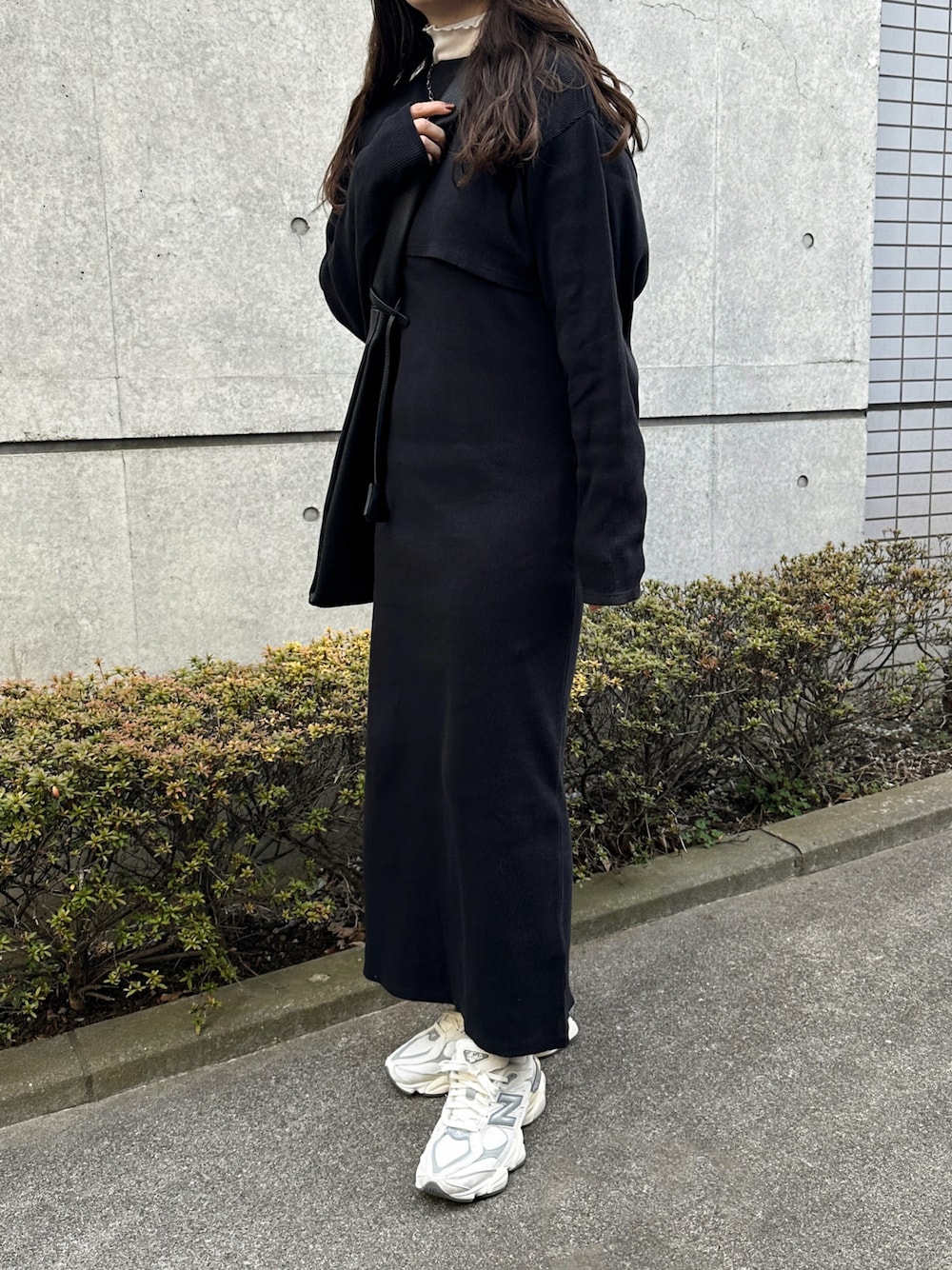 ブラック系のワンピース、ブラック系のトートバッグ、ホワイト系のスニーカーを着用したレディースの冬コーディネートの1枚目の写真