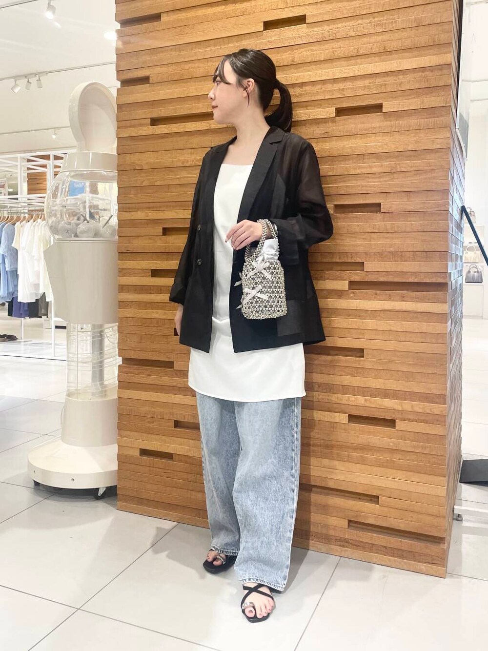 ブルー系のデニムパンツ、グレー系のハンドバッグ、ホワイト系のワンピースを着用したレディースの夏コーディネートの1枚目の写真