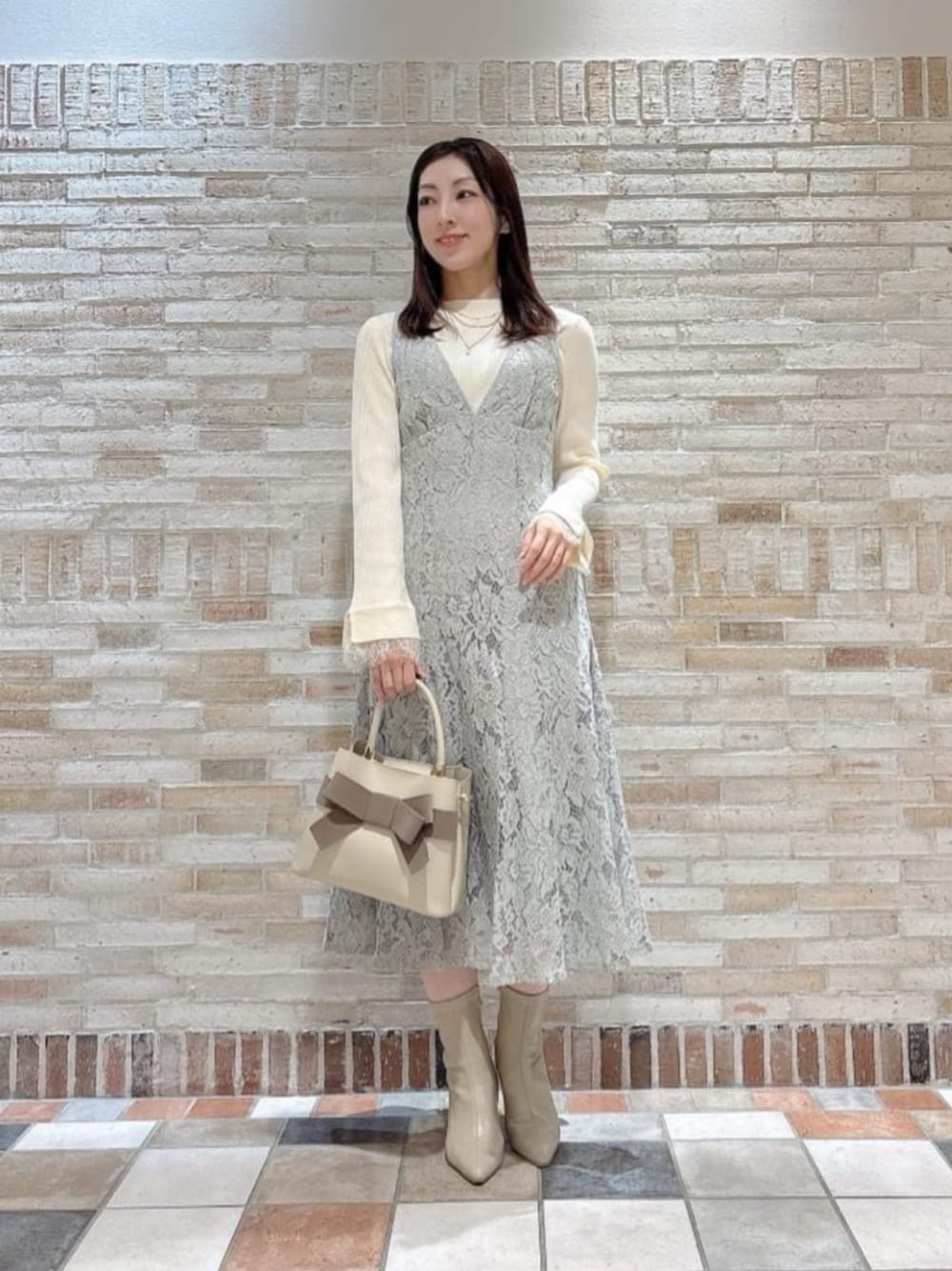 ホワイト系のニット/セーター、ベージュ系のショルダーバッグ、グリーン系のワンピースを着用したレディースの冬コーディネートの1枚目の写真