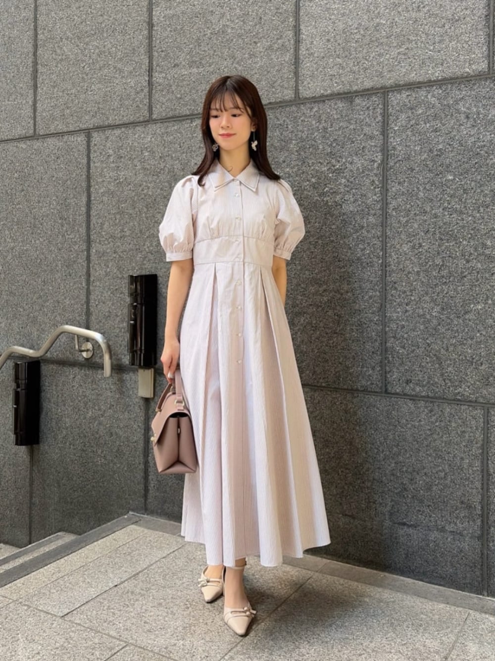 ベージュ系のパンプス、ベージュ系のワンピース、ブラウン系のトートバッグを着用したレディースの春コーディネートの1枚目の写真