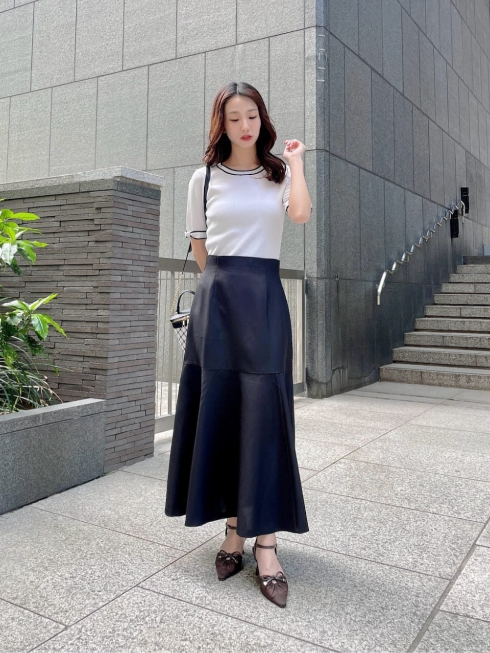 ホワイト系のニット/セーター、ブラック系のスカートを着用したレディースの春コーディネートの1枚目の写真