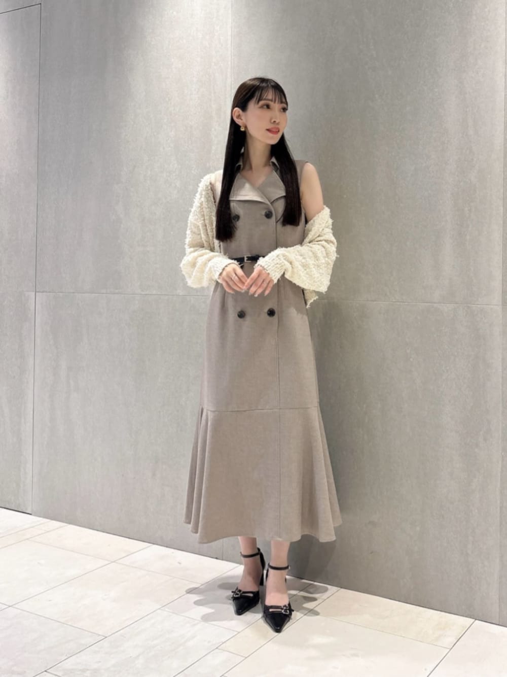 ブラック系のパンプス、ホワイト系のカーディガン/ボレロ、ベージュ系のワンピースを着用したレディースの春コーディネートの1枚目の写真