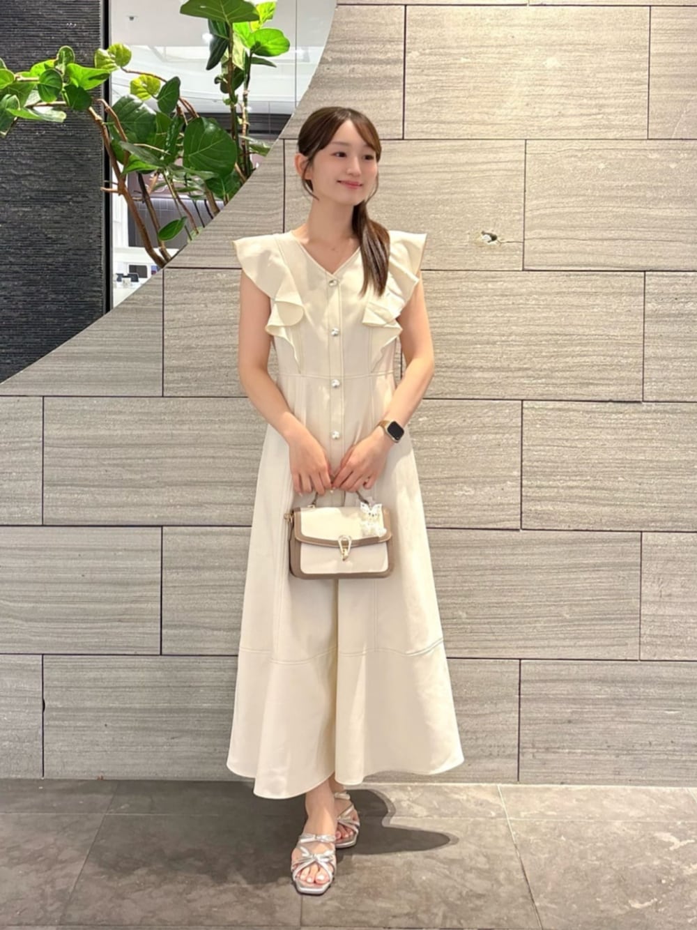シルバー系のパンプス、グレー系のショルダーバッグ、ベージュ系のワンピースを着用したレディースの夏コーディネートの1枚目の写真