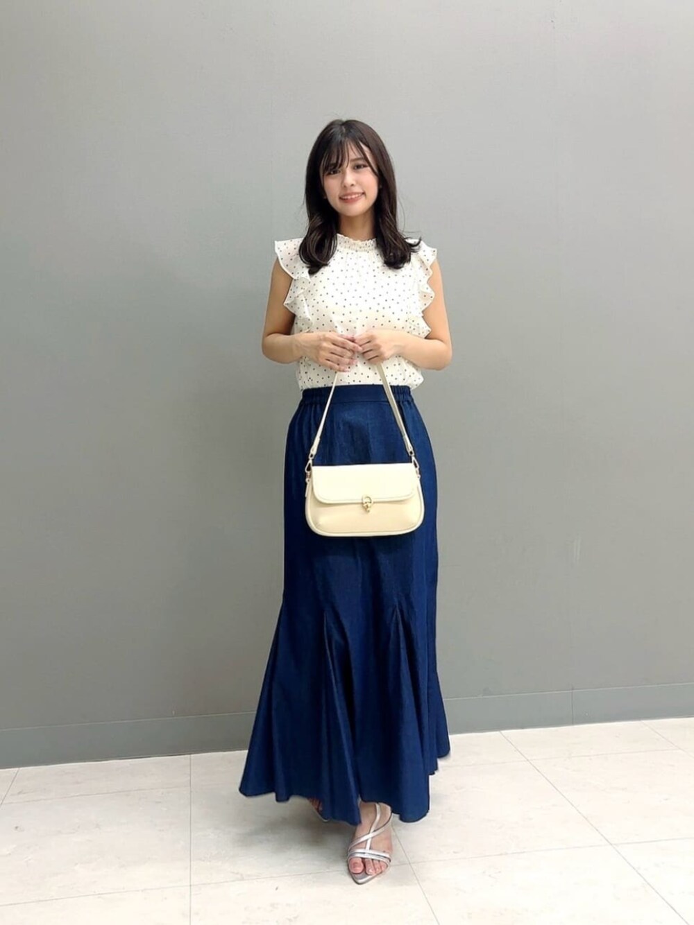 ホワイト系のショルダーバッグ、シルバー系のパンプス、ホワイト系のシャツ/ブラウスを着用したレディースの夏コーディネートの1枚目の写真