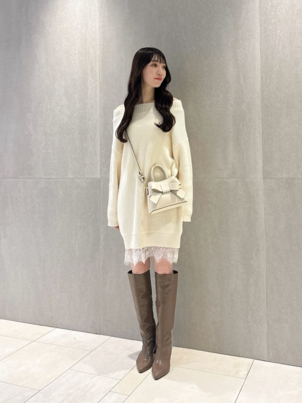 ブラウン系のブーツ、ホワイト系のショルダーバッグ、ホワイト系のワンピースを着用したレディースの春コーディネートの1枚目の写真