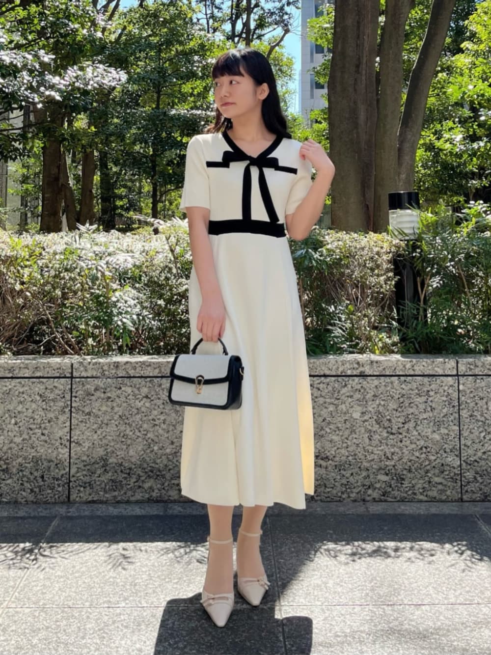 ホワイト系のワンピース、ベージュ系のパンプスを着用したレディースの春コーディネートの1枚目の写真