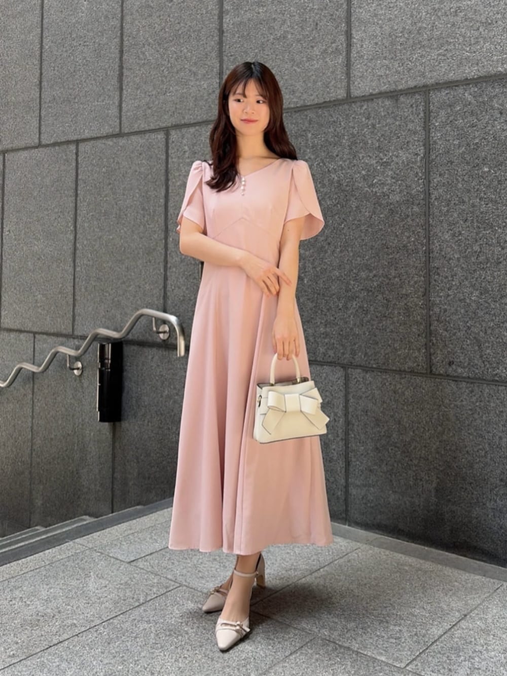ホワイト系のショルダーバッグ、ベージュ系のパンプス、ピンク系のワンピースを着用したレディースの春コーディネートの1枚目の写真