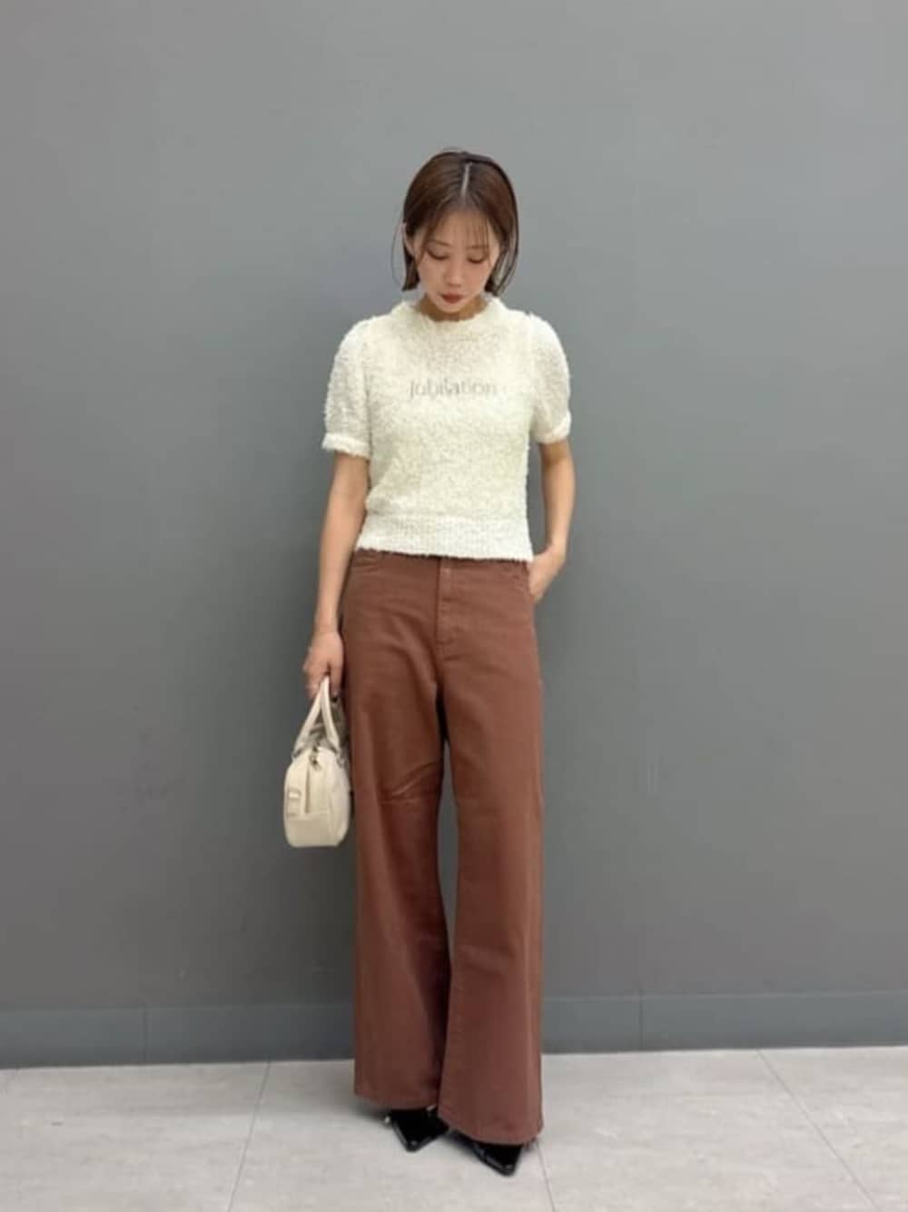 ブラウン系のデニムパンツ、ホワイト系のボストンバッグ、ホワイト系のニット/セーターを着用したレディースの秋コーディネートの1枚目の写真