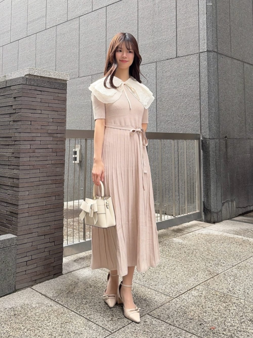 ホワイト系のショルダーバッグ、ベージュ系のパンプス、ベージュ系のワンピースを着用したレディースの春コーディネートの1枚目の写真
