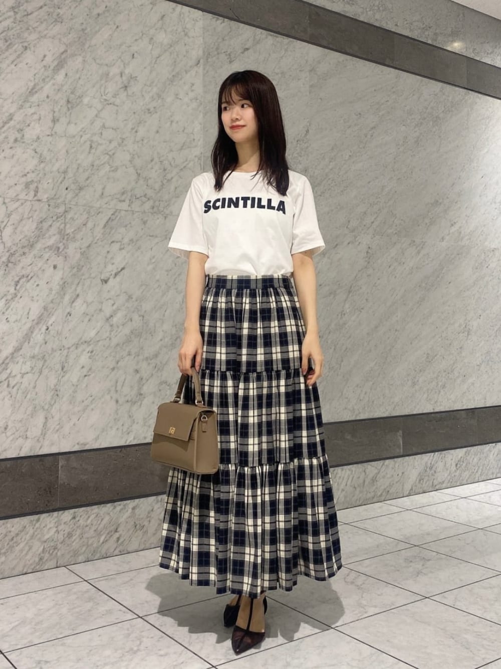 ホワイト系のTシャツ/カットソー、ベージュ系のスカートを着用したレディースの秋コーディネートの1枚目の写真
