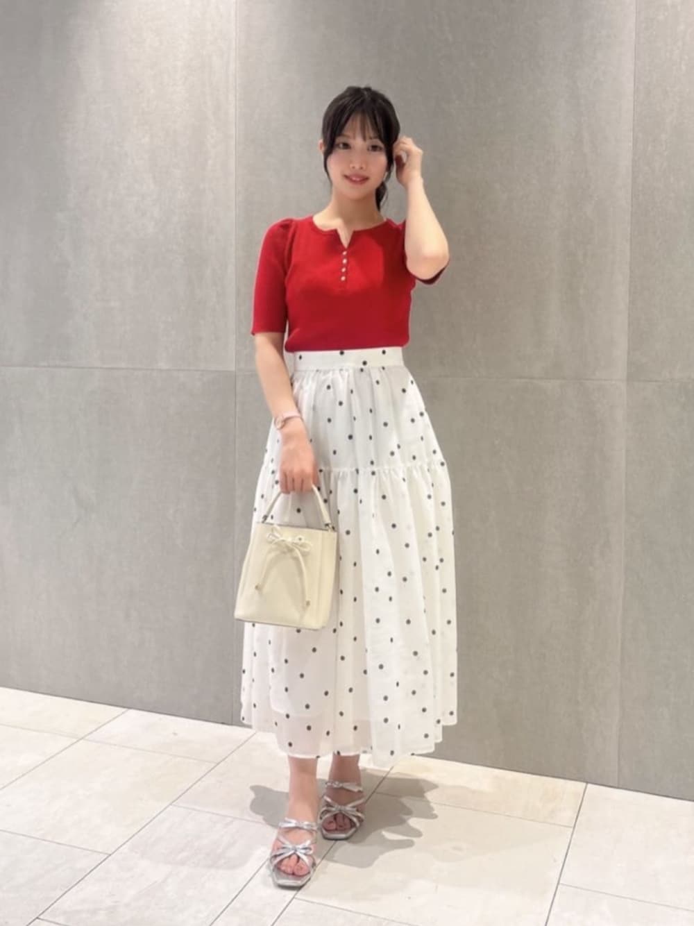 ホワイト系のショルダーバッグ、シルバー系のパンプス、レッド系のニット/セーターを着用したレディースの春コーディネートの1枚目の写真