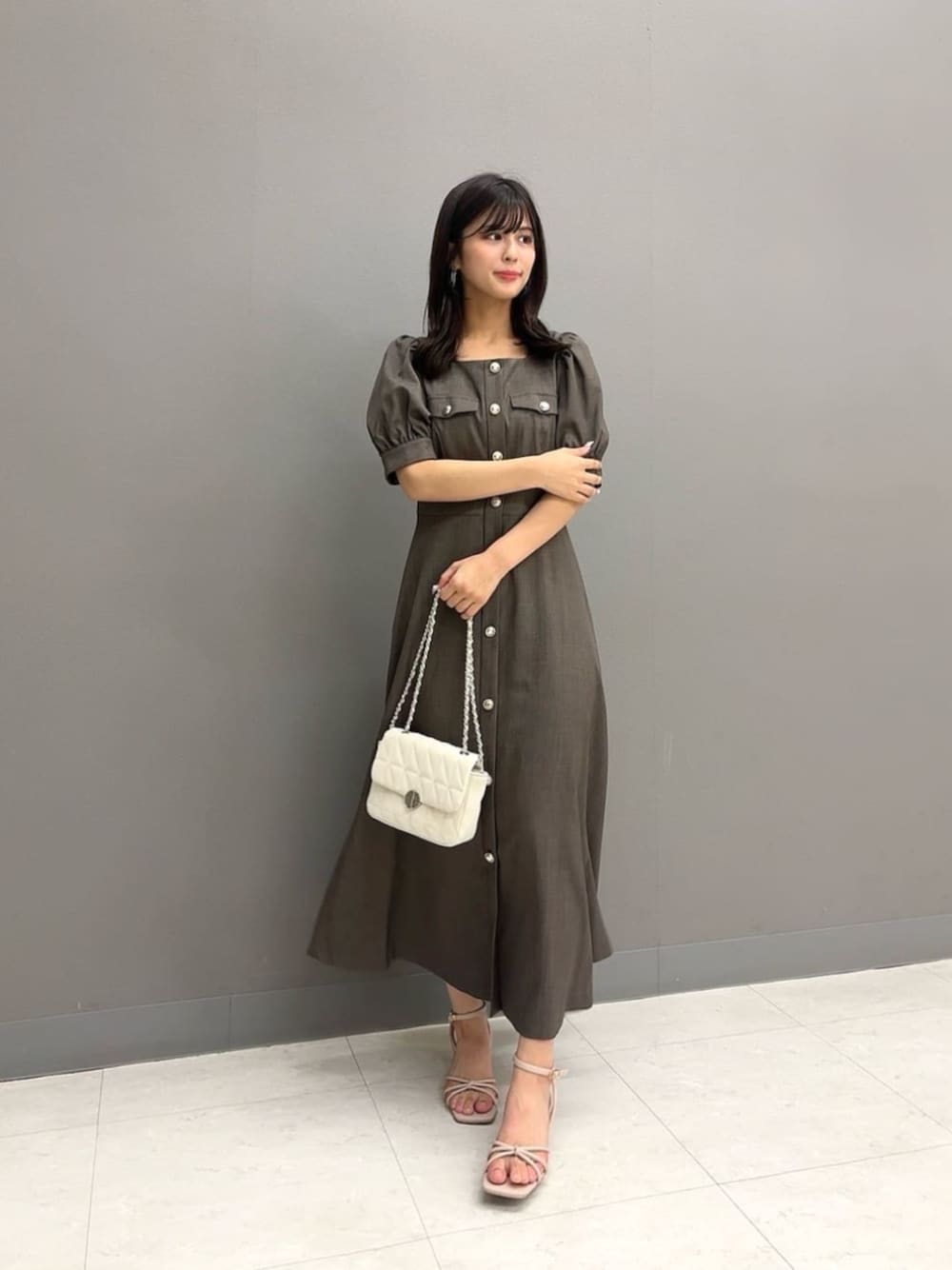 ホワイト系のショルダーバッグ、ブラウン系のワンピースを着用したレディースの夏コーディネートの1枚目の写真
