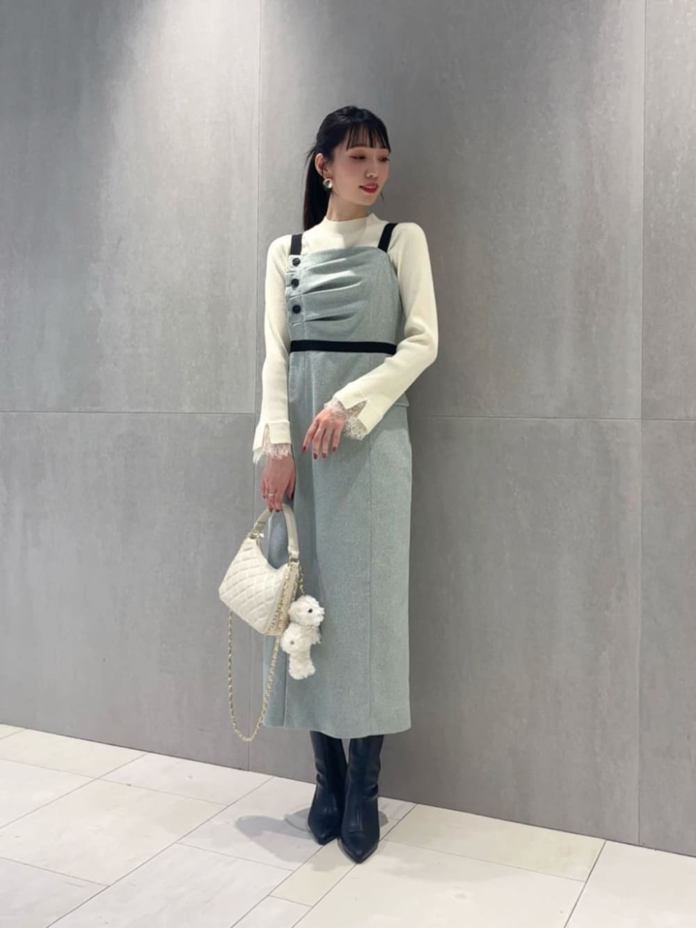 ホワイト系のショルダーバッグ、ホワイト系のニット/セーター、グレー系のワンピースを着用したレディースの冬コーディネートの1枚目の写真