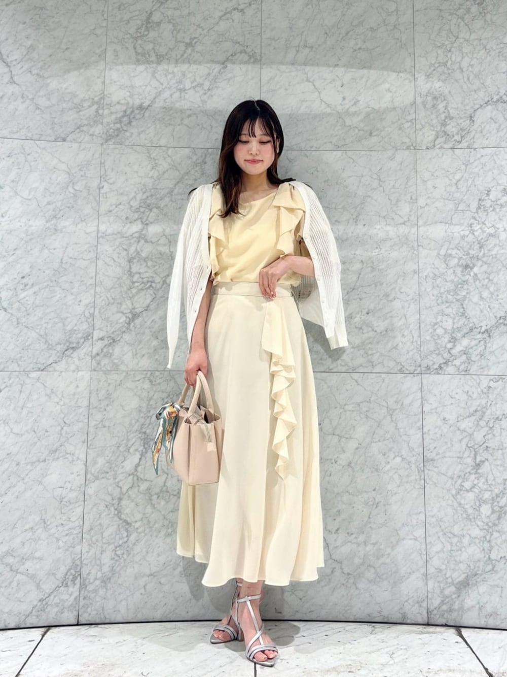 シルバー系のパンプス、ホワイト系のカーディガン/ボレロ、ベージュ系のトートバッグを着用したレディースの春コーディネートの1枚目の写真