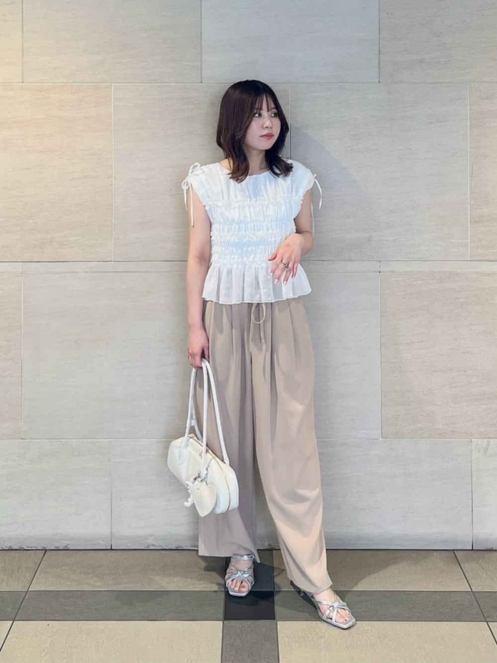 ホワイト系のショルダーバッグ、シルバー系のパンプス、ホワイト系のシャツ/ブラウスを着用したレディースの夏コーディネートの1枚目の写真