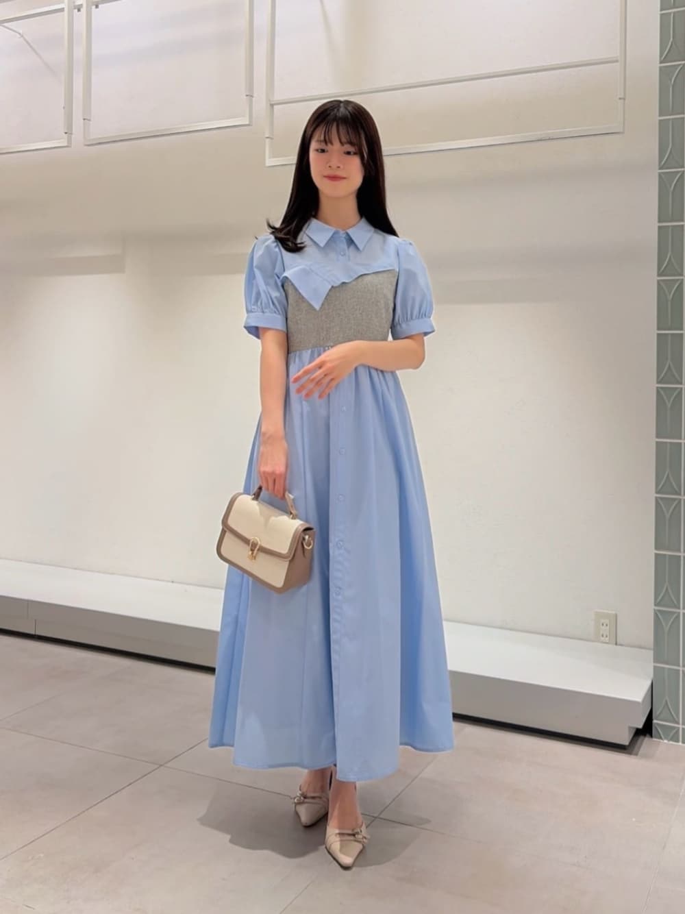 ベージュ系のパンプス、グレー系のショルダーバッグ、ブルー系のワンピースを着用したレディースの春コーディネートの1枚目の写真