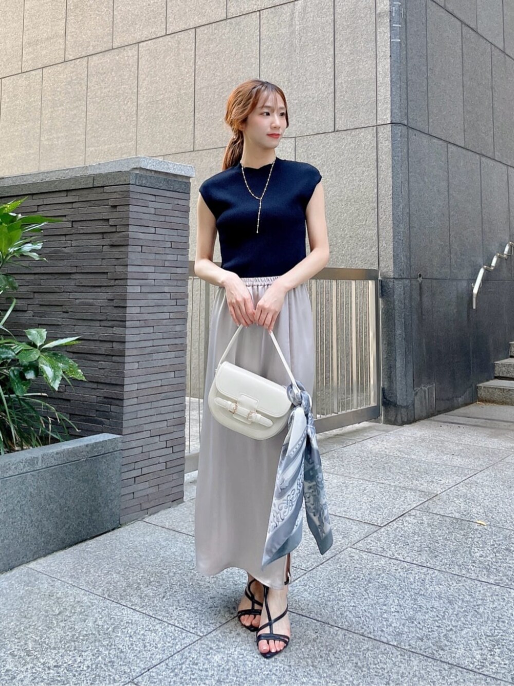 ブラック系のパンプス、ブラック系のニット/セーター、ベージュ系のスカートを着用したレディースの夏コーディネートの1枚目の写真